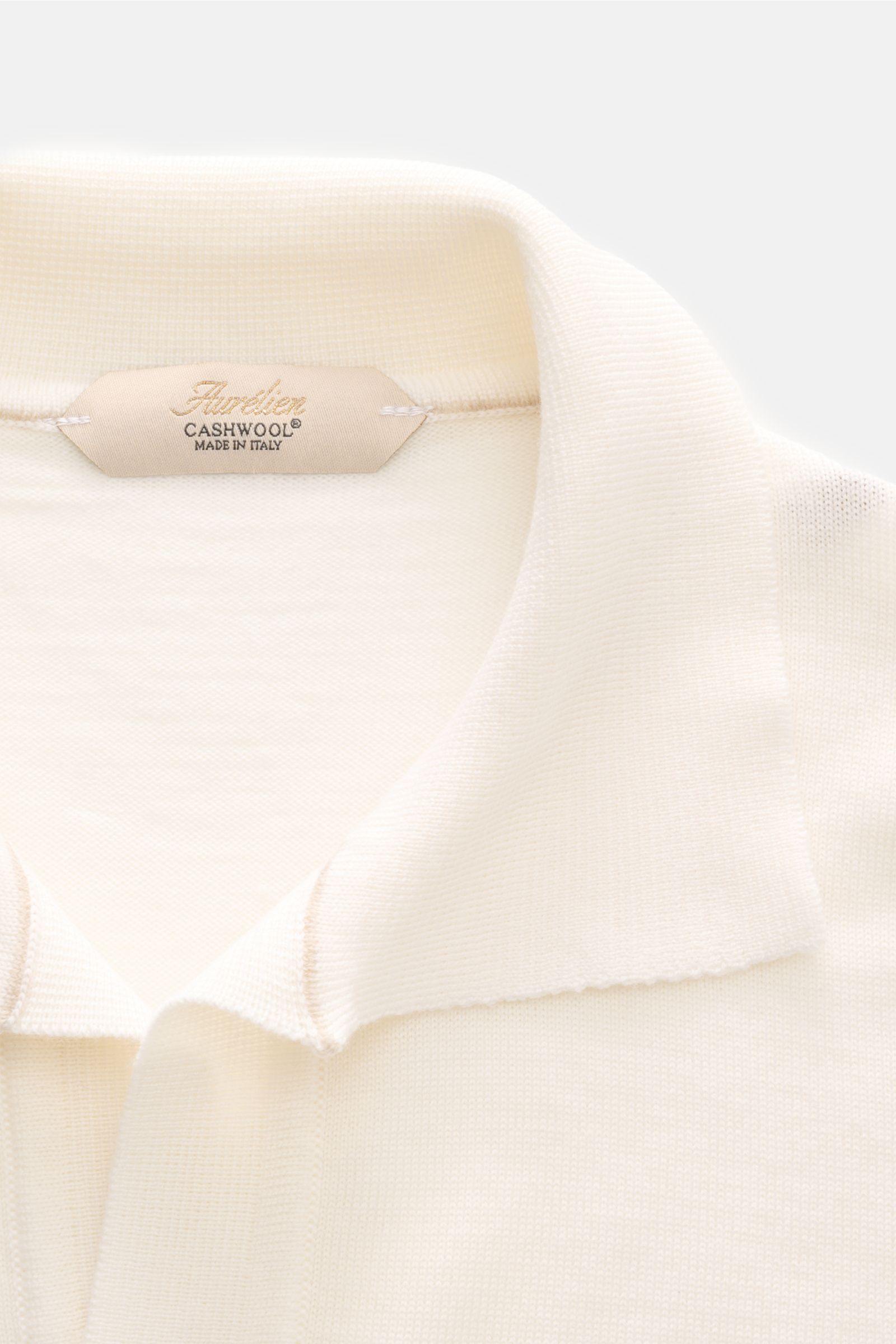 Close-up front view of Aurélien Kurzarm-Strickpolo 'Cashwool' offwhite, showcasing the classic polo collar and fine knit texture with the label inside.

Frühlings-Essential: Das Kurzarm-Strickpolo von AURÉLIEN aus exklusiver 'Cashwool'-Merinowolle vere