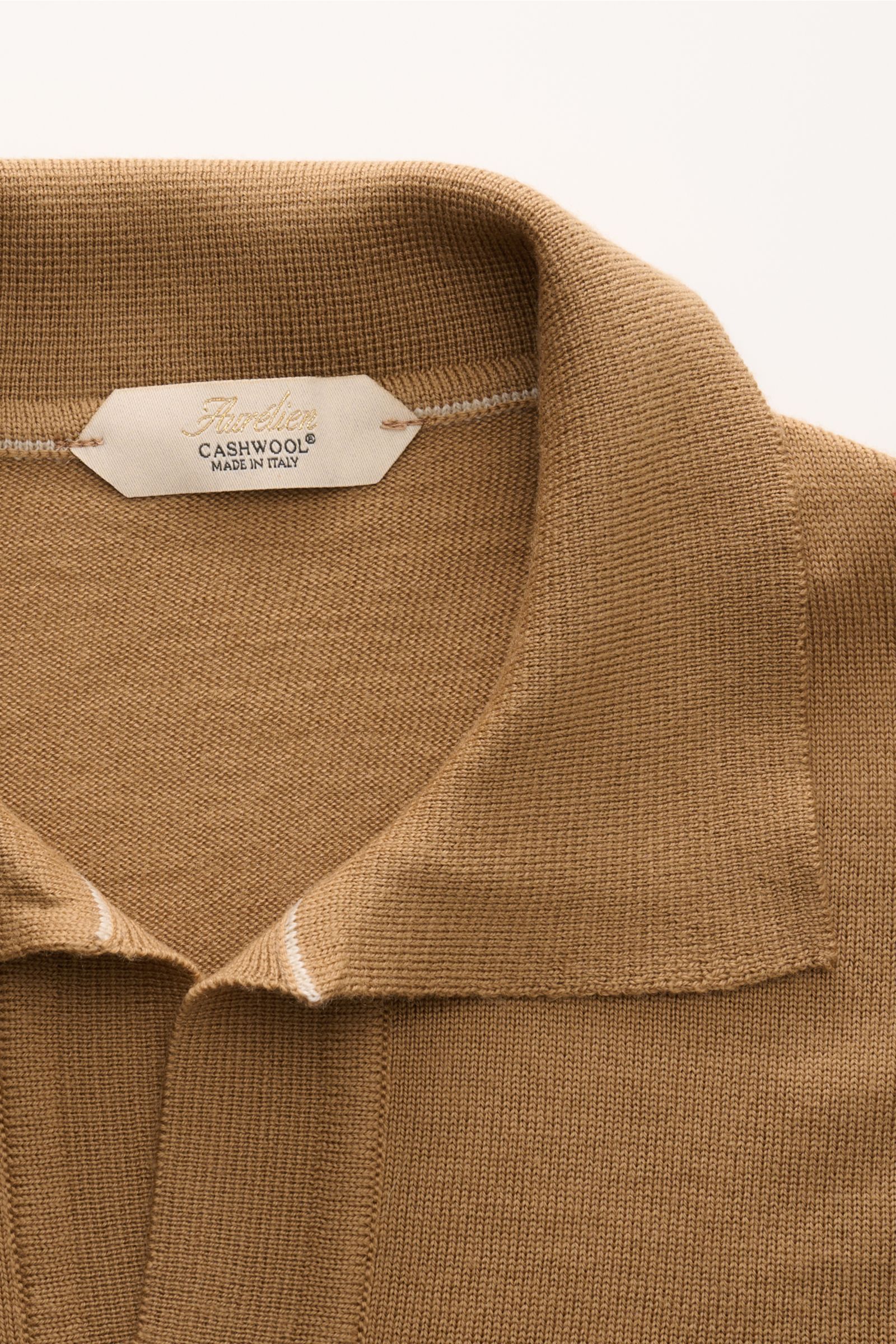 Aurélien Strickpolo 'Cashwool' hellbraun shown from above, highlighting the classic polo collar, open placket, and fine knit texture. Frühlings-Essential: Das Strickpolo von AURÉLIEN aus exklusiver 'Cashwool'-Merinowolle vereint edle Haptik mit zeitloser 