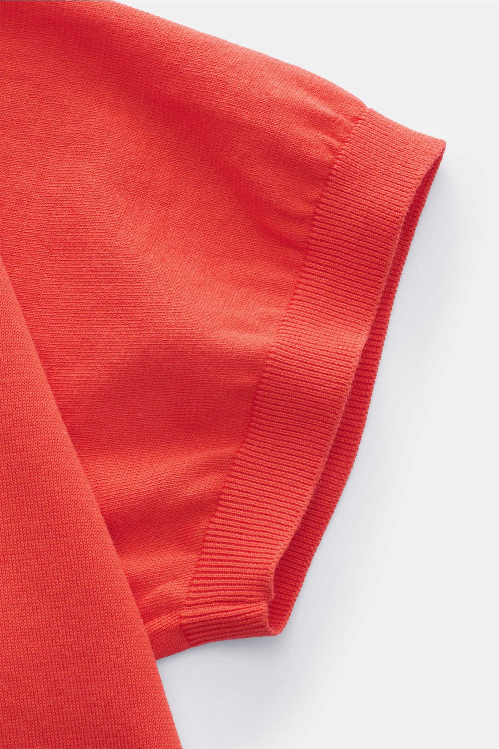 Nahaufnahme des Ärmels vom Drumohr Kurzarm-Strickpolo rot, feines Baumwoll-Feinstrick mit elastischem Rippbündchen, von oben fotografiert.