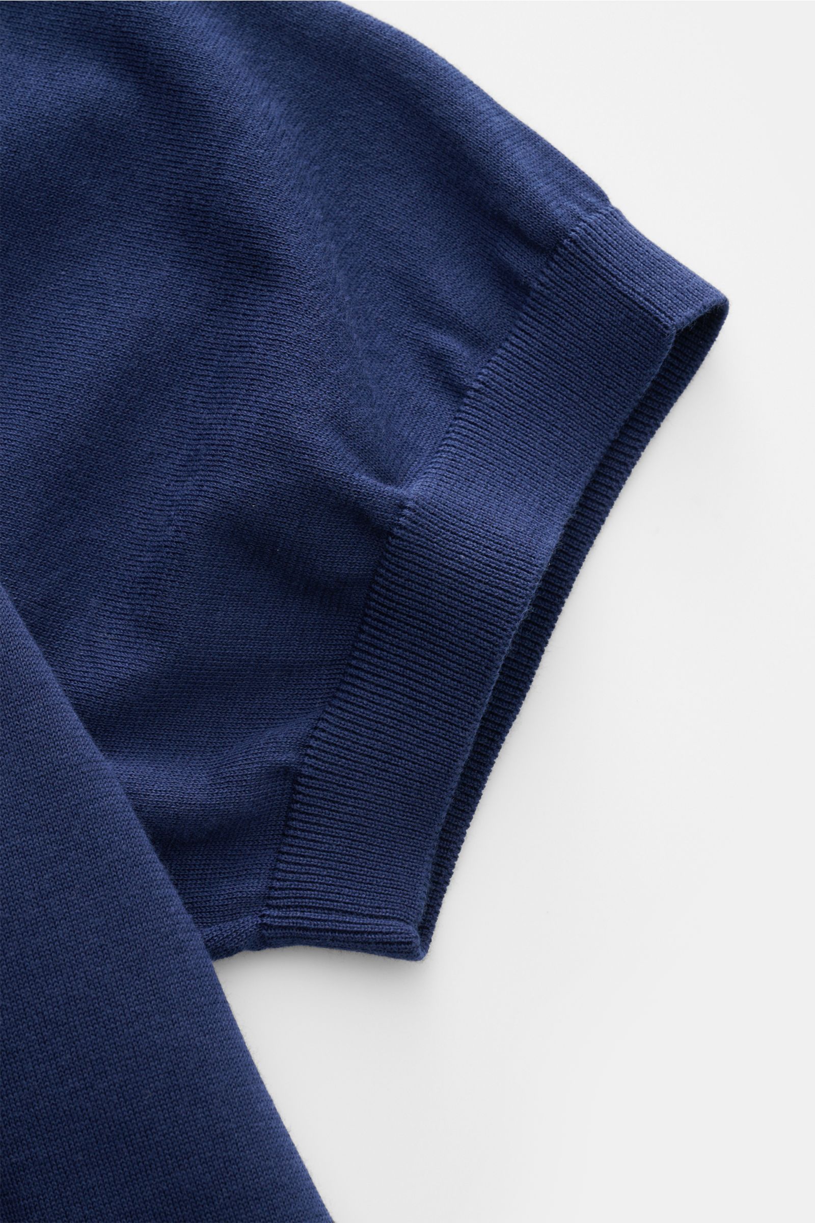 Nahaufnahme des Ärmels von Drumohr Kurzarm-Strickpolo dunkelblau, feiner Baumwoll-Feinstrick mit elastischem Rippbündchen, seitliche Perspektive.