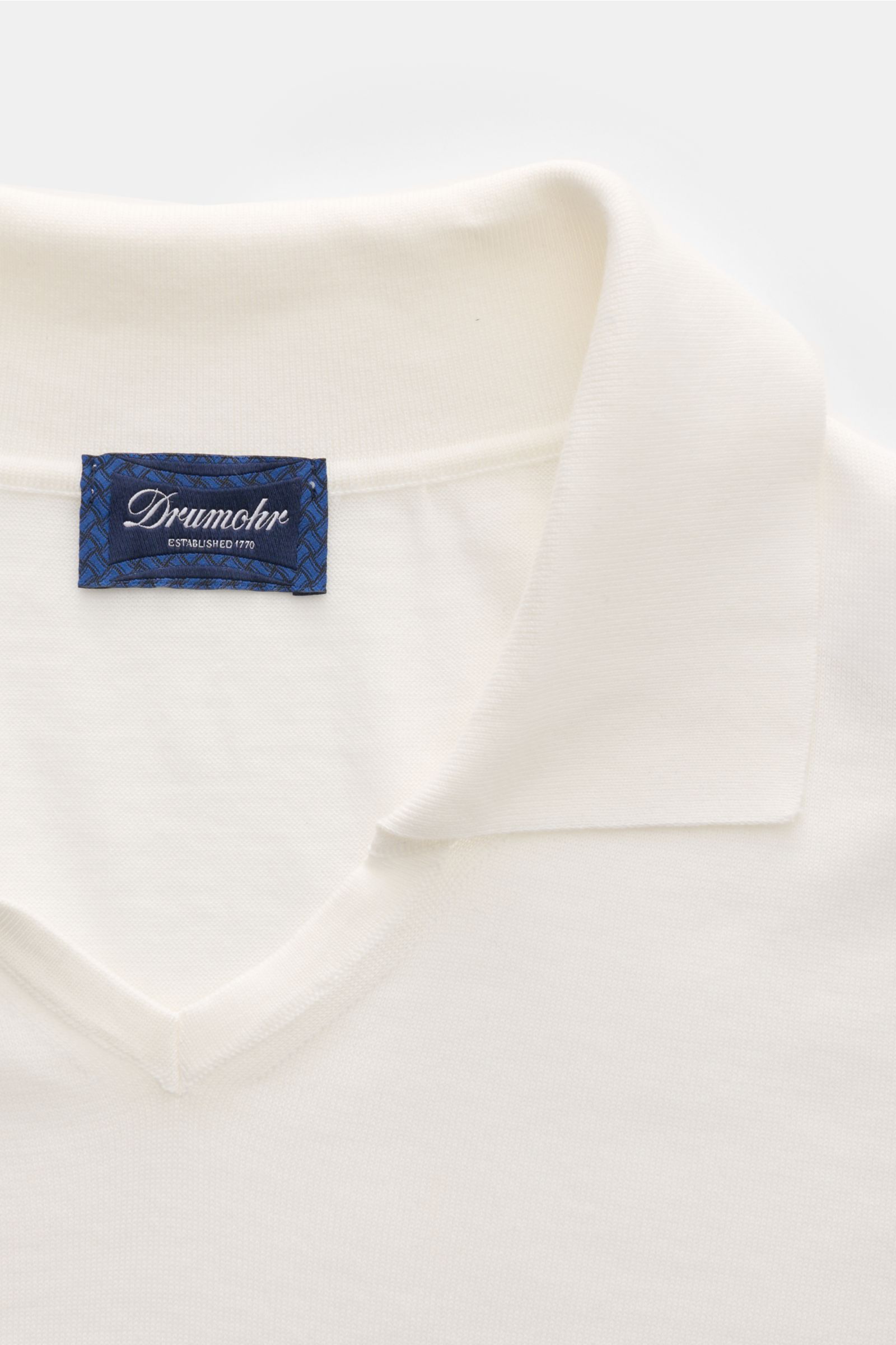 Close-up front view of Drumohr Short sleeve knit polo shirt off-white showing soft cotton knit, open collar placket, and blue label.

Description: A fine essential from label DRUMOHR: This Italian-made short sleeve knit polo is made of comfortably soft