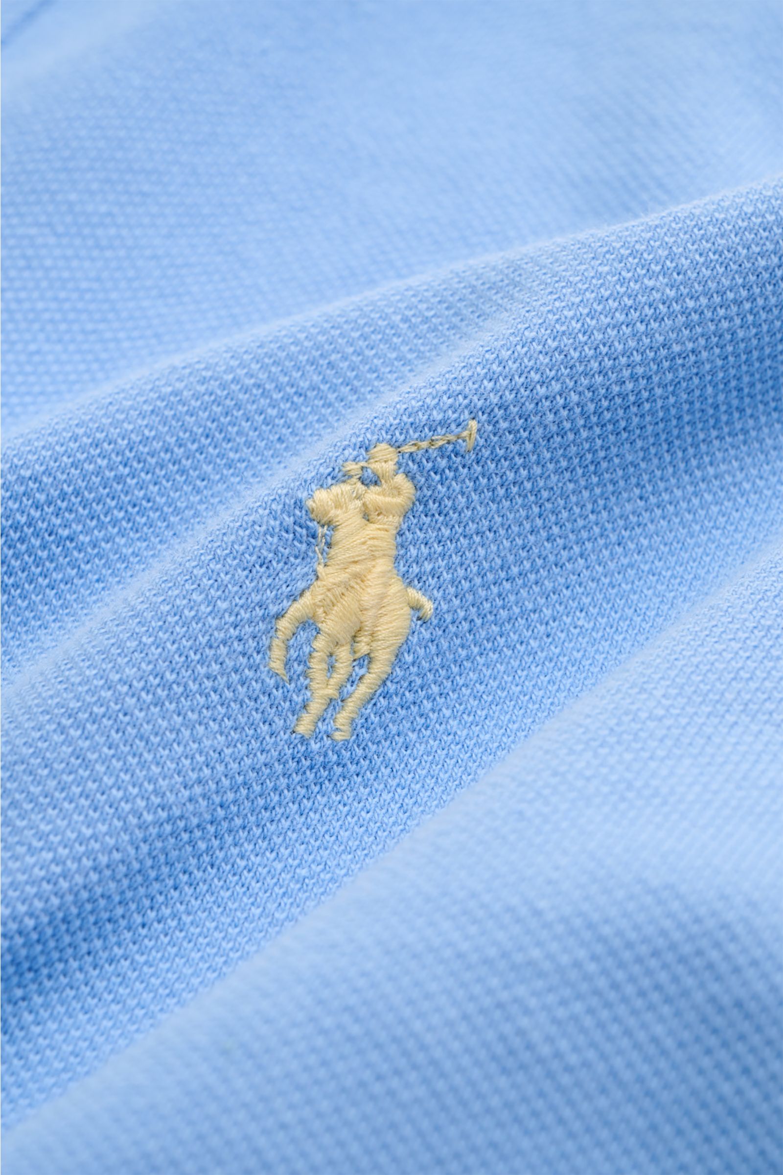 Nahaufnahme des hellblauen Polo Ralph Lauren Poloshirts mit feiner Piqué-Struktur und ikonischem Poloreiter-Stitching, Detail von Jersey aus reiner Baumwolle.