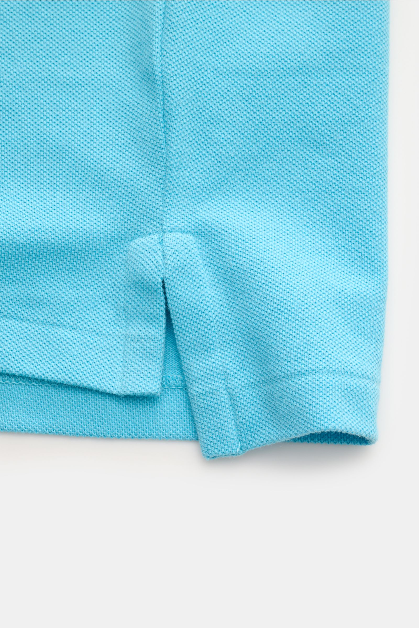 Nahaufnahme des seitlichen Saums und Saumschlitzes eines Polo Ralph Lauren Poloshirts azurblau aus reiner Baumwolle mit Piqué-Struktur.