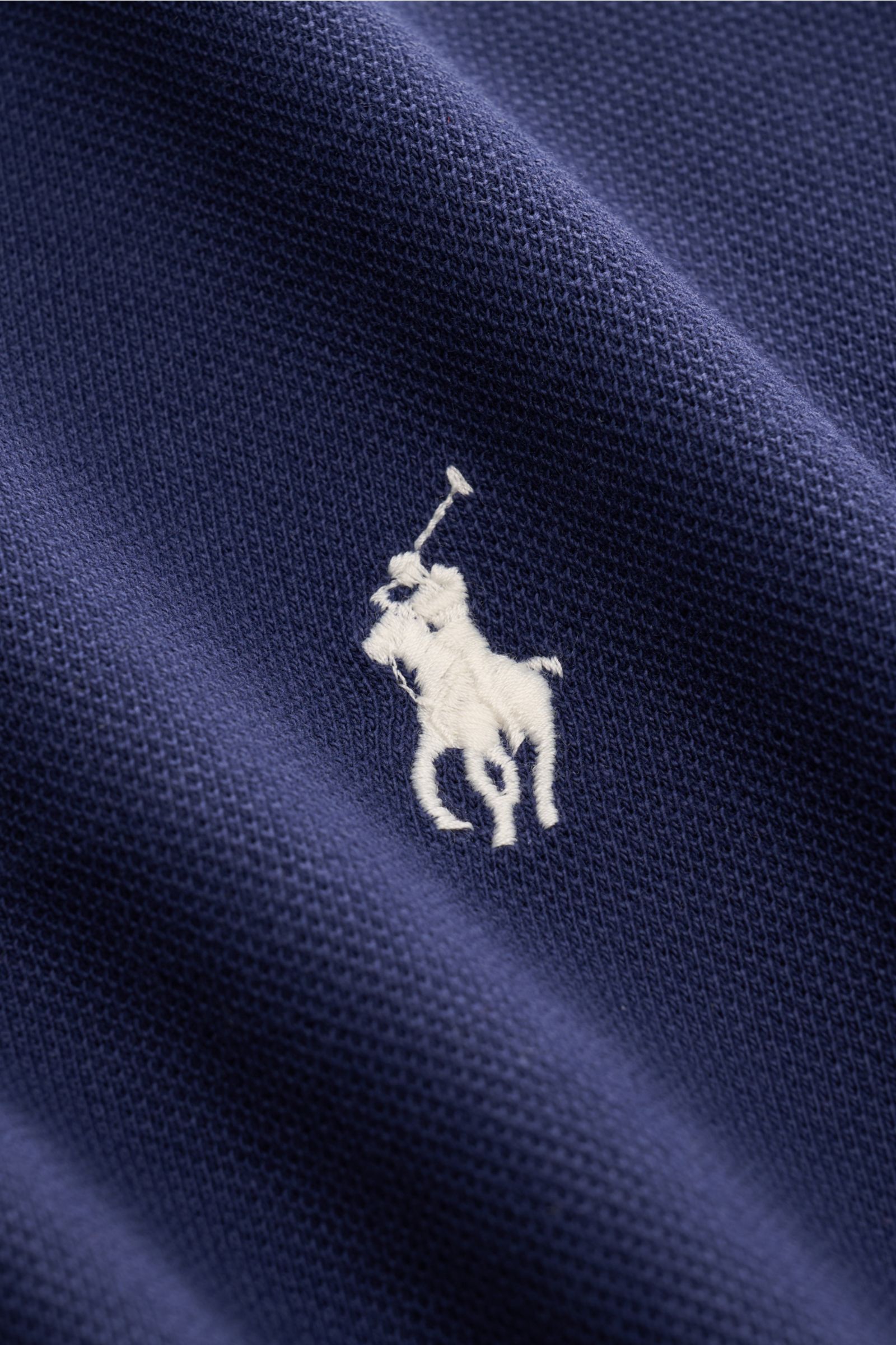 Close-up view of the navy fabric and iconic white polo rider logo stitching on the chest of the Polo Ralph Lauren Polo shirt navy, showcasing the fine piqué texture and high-quality cotton material. The classic among polo shirts since 1972: The iconic 
