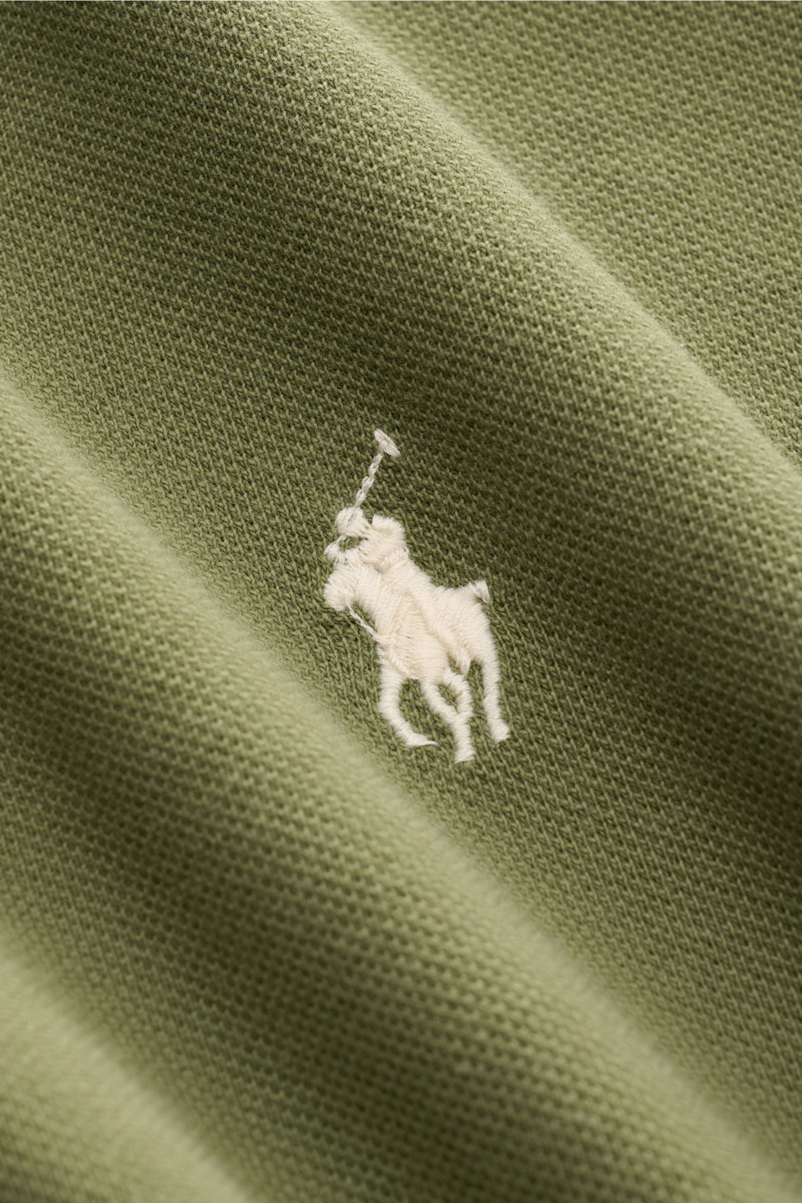 Close-up perspective of Polo Ralph Lauren Polo shirt olive showing fine piqué texture and iconic white polo rider stitching on olive pure cotton fabric. The classic among polo shirts since 1972: The iconic pure cotton piqué model with the famous polo ride