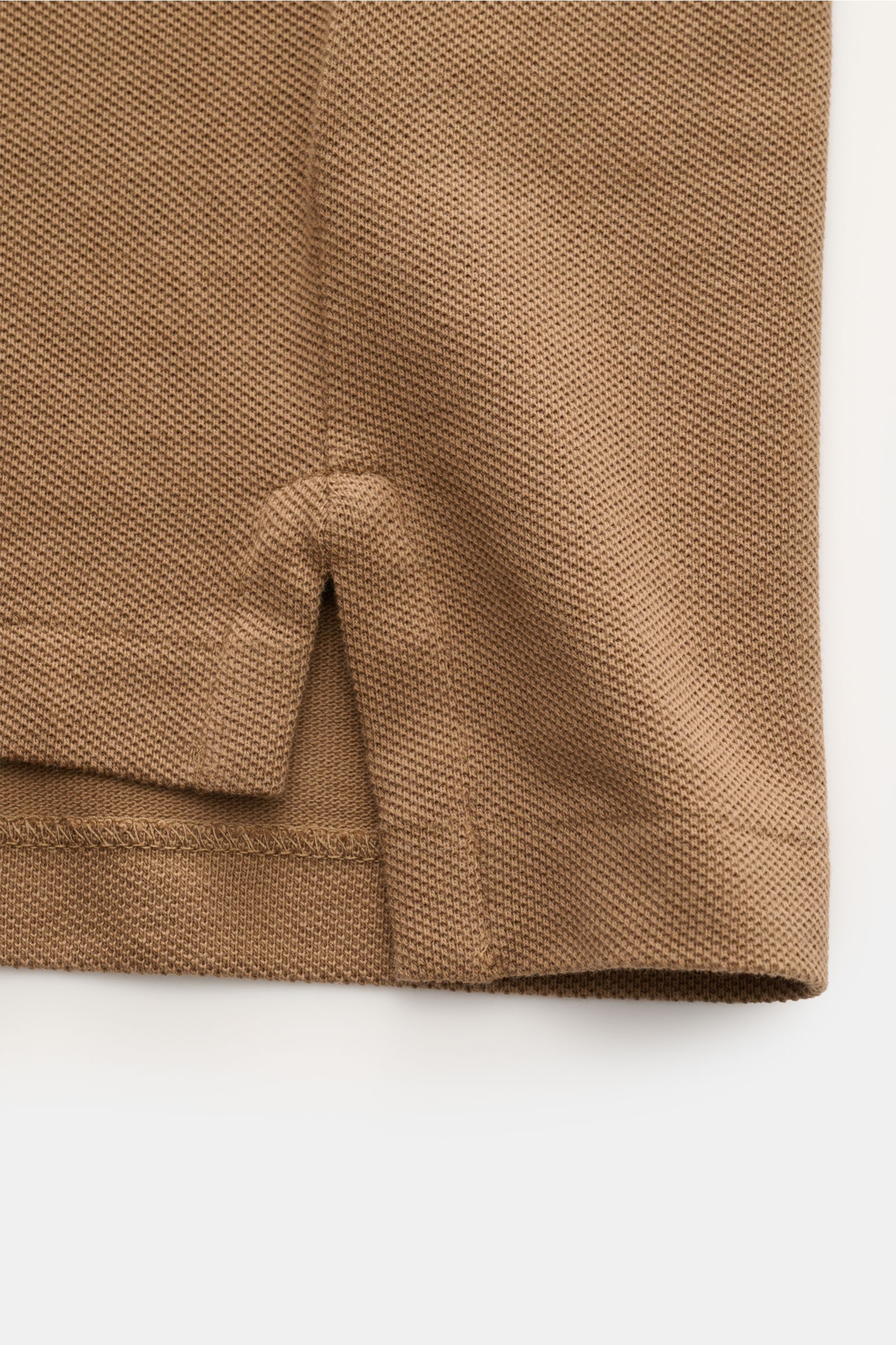 Nahaufnahme des seitlichen Saums mit Schlitz des braunen Polo Ralph Lauren Poloshirt aus reiner Baumwolle mit feiner Piqué-Struktur.
