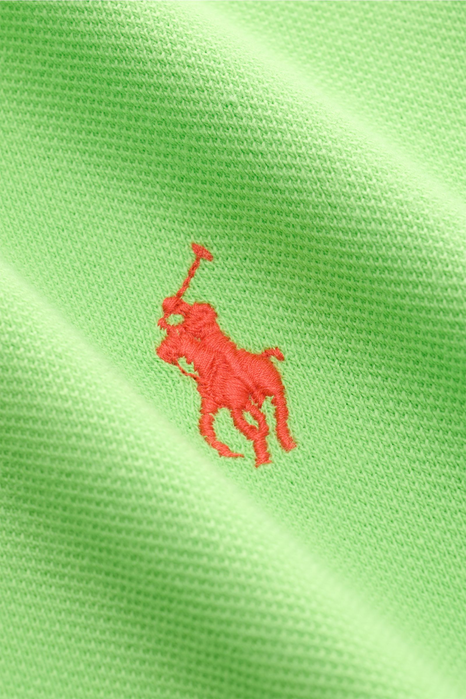 Nahaufnahme des Polo Ralph Lauren Poloshirts neongrün aus reiner Baumwolle mit feiner Piqué-Struktur und rotem Poloreiter-Stitching auf der Brust.