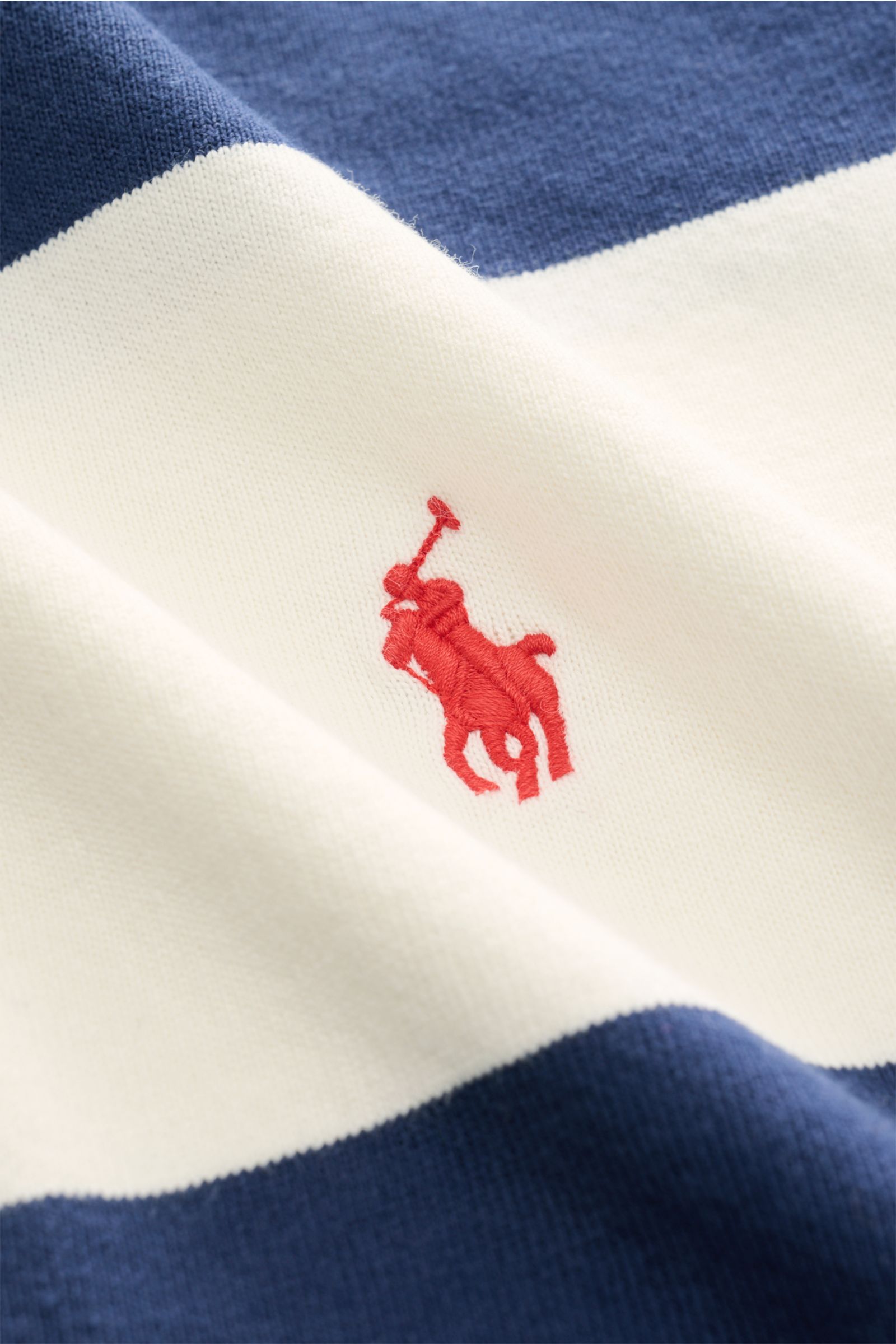 Close-up view of Polo Ralph Lauren Polo shirt navy/off-white striped showing detailed fabric texture and red polo rider logo stitching.

The absolute classic among polo shirts since 1972: The iconic pure cotton polo shirt with the legendary polo rider 