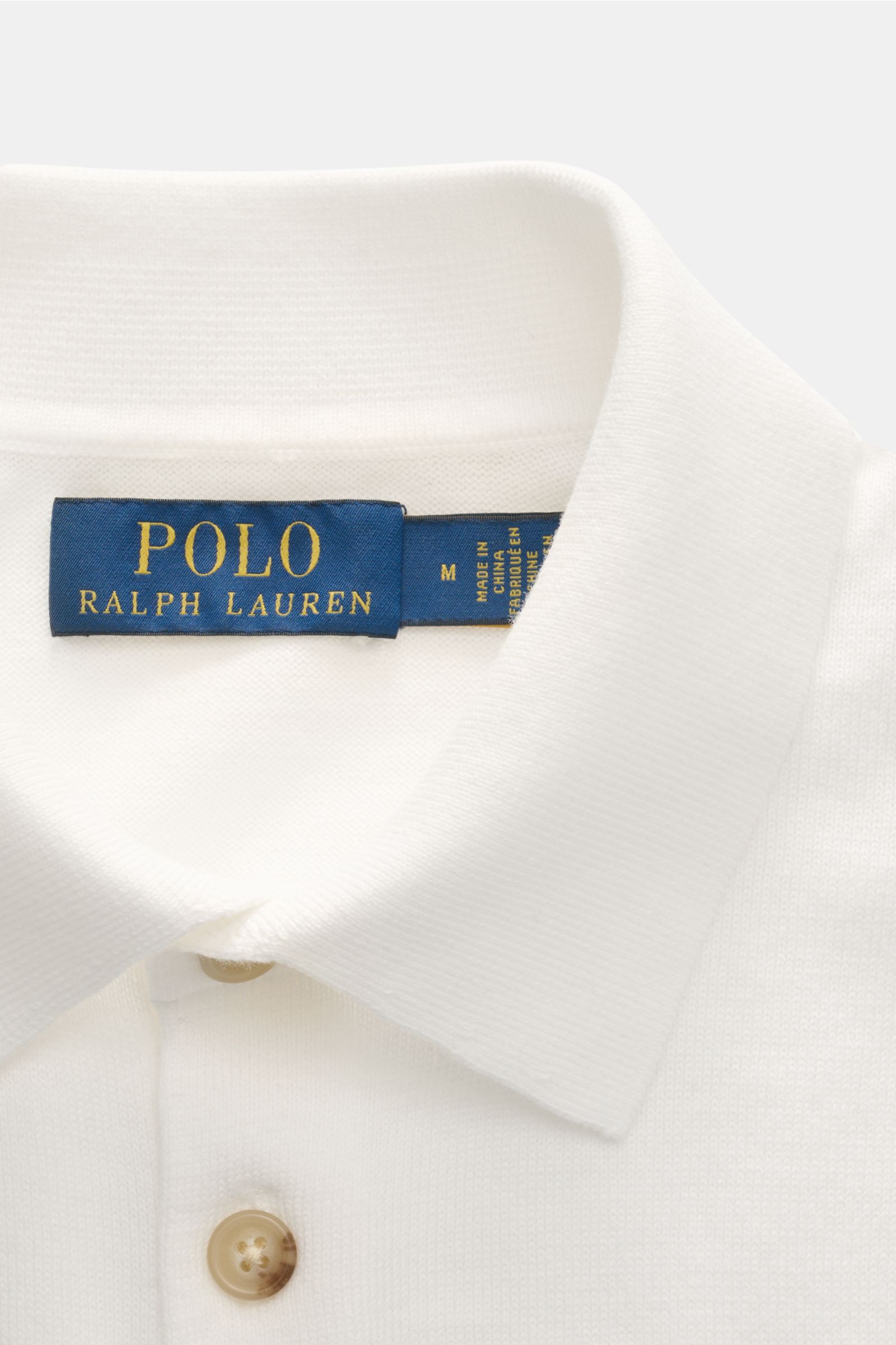 Close-up front view of Polo Ralph Lauren Kurzarm-Strickpolo offwhite showing collar, three-button placket, and label.  
Sommerlicher Klassiker: Das Kurzarm-Strickpolo von POLO RALPH LAUREN verbindet zeitloses Design mit höchstem Tragekomfort.

