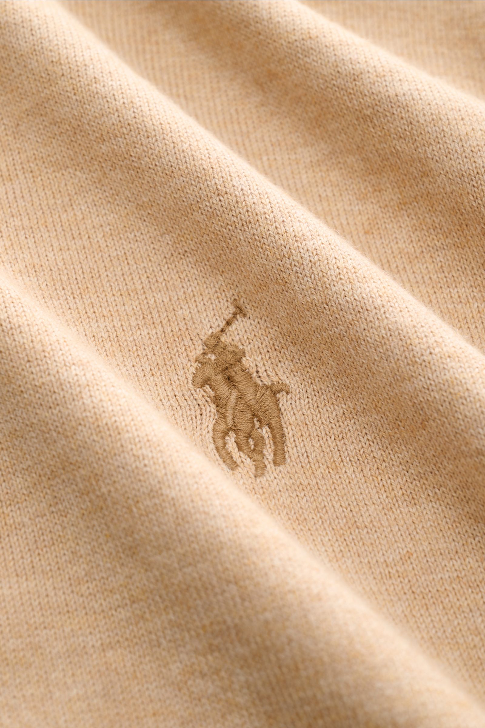 Close-up front view of beige melange fine-knit fabric with embroidered Polo Ralph Lauren logo, showing texture and soft grip of Polo Ralph Lauren Kurzarm-Strickpolo beige meliert. Sommerlicher Klassiker: Das Kurzarm-Strickpolo von POLO RALPH LAUREN ver