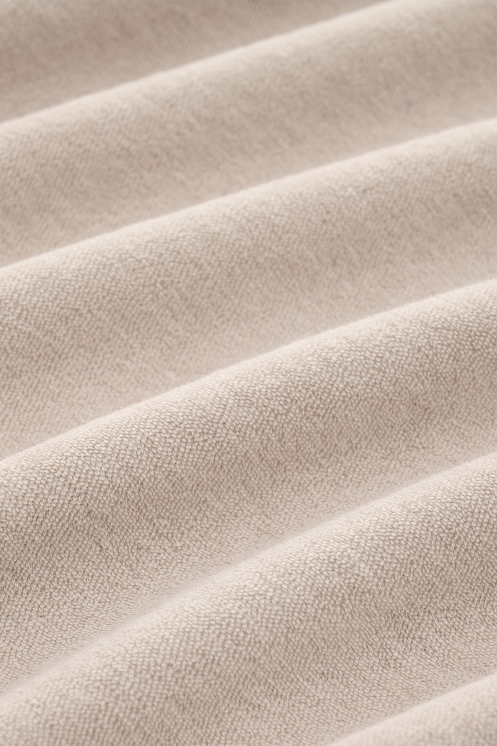 Close-up front view of 04651/ A trip in a bag Terry polo shirt 'Terry Johnny' beige showing soft cotton terry fabric texture with folds. Holiday feel you can wear: This short sleeve polo shirt in comfortable cotton terry by 04651/ A TRIP IN A BAG is a cas