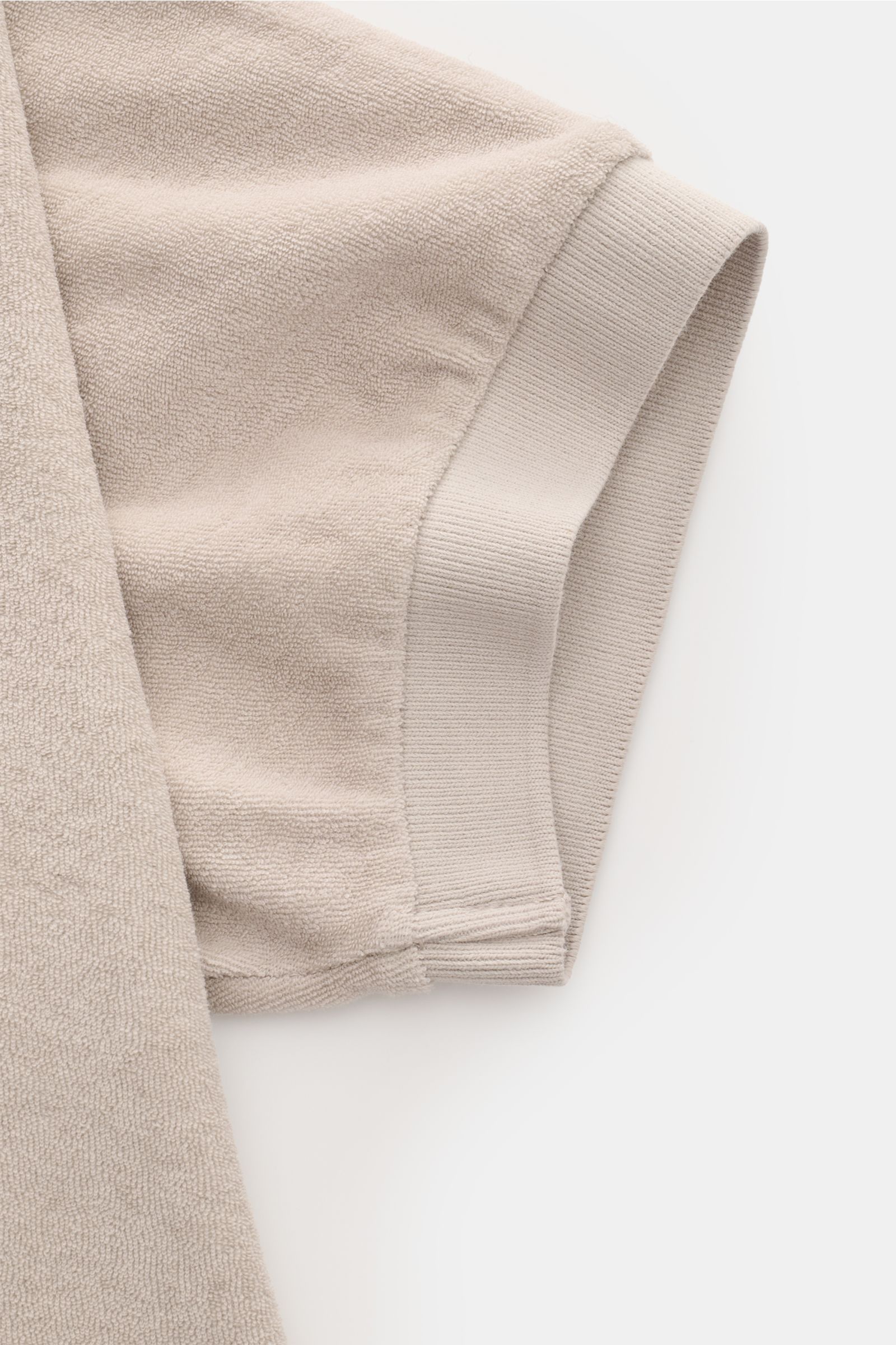 Close-up angled view of the short sleeve cuff of the 04651/ A trip in a bag Terry polo shirt 'Terry Johnny' beige, showcasing terrycloth cotton fabric. Holiday feel you can wear: This short sleeve polo shirt in comfortable cotton terry by 04651/ A TRIP IN
