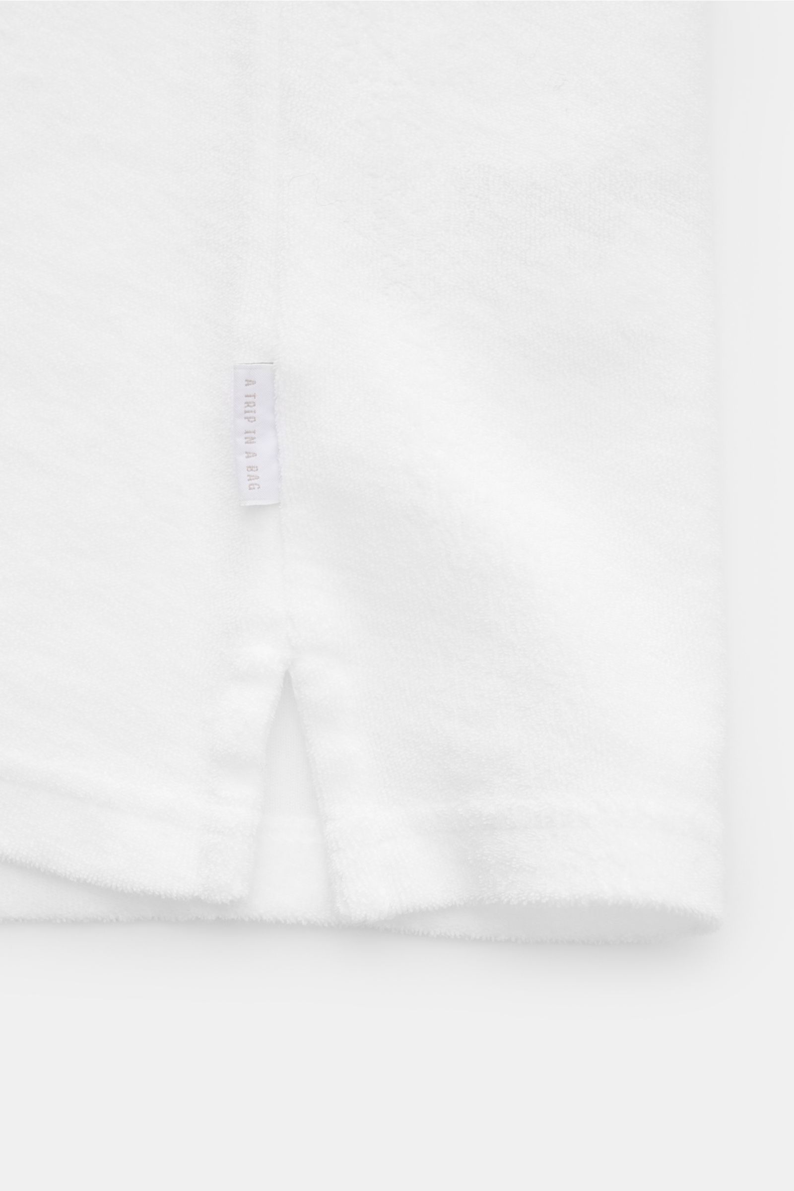 Close-up side hem view of 04651/ A trip in a bag Terry polo shirt 'Terry Johnny' white in soft cotton terry with small side label and hem vents.