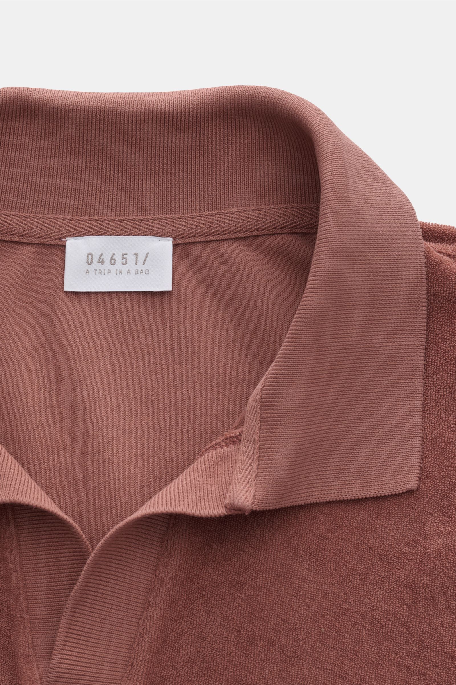 Nahaufnahme aus schräger Draufsicht des 04651/ A trip in a bag Frottee-Poloshirt 'Terry Johnny' rostbraun mit Polokragen, offener Leiste und Baumwoll-Frottee.