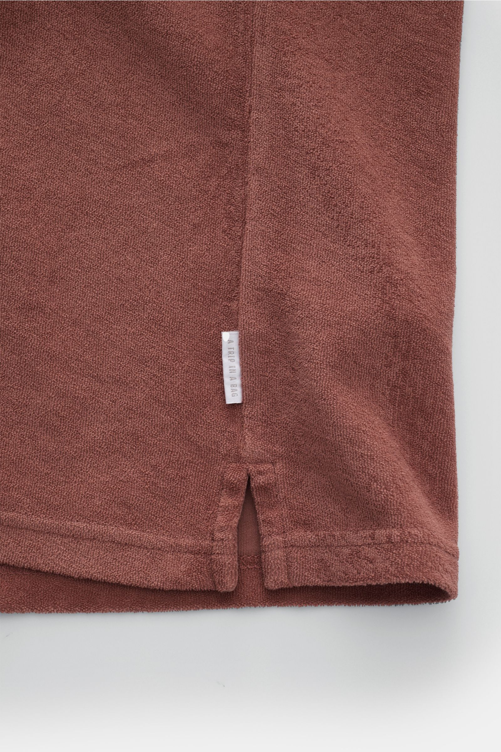 04651/ A trip in a bag Frottee-Poloshirt 'Terry Johnny' rostbraun, Detailansicht Saum mit kurzem Schlitz und kleinem Weblabel aus weichem Baumwoll-Frottee.