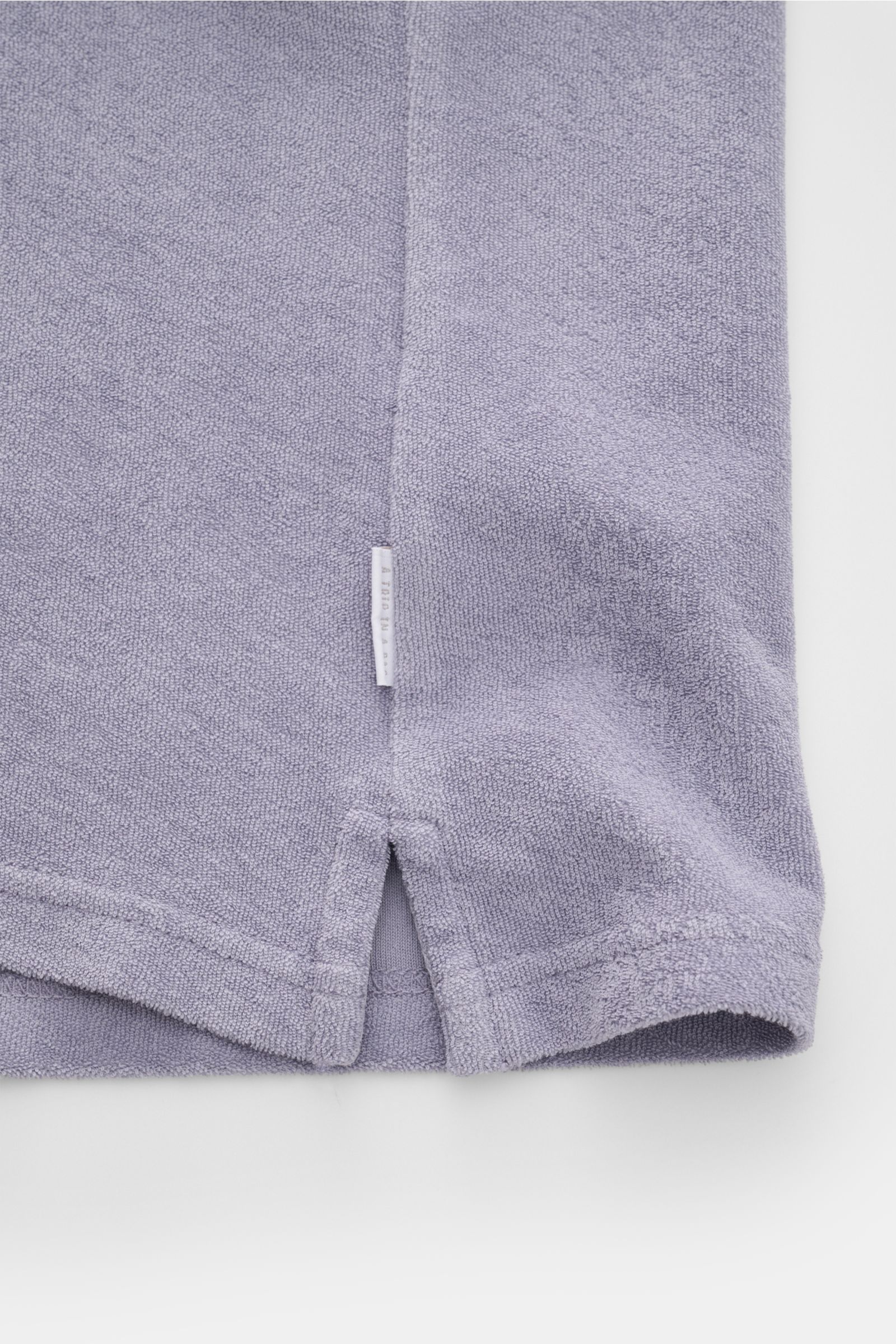 04651/ A trip in a bag Frottee-Poloshirt 'Terry Johnny' lavender, Detailfoto Saum und Weblabel, Baumwoll-Frottee, Regular Fit, offener Polokragen, kurze Saumschlitze, weicher Griff, Perspektive von unten auf den unteren Shirtbereich.