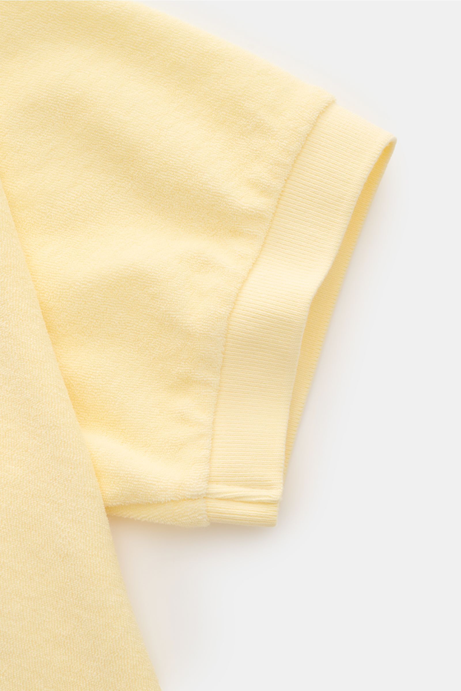 Close-up side view of the short sleeve cuff of the 04651/ A trip in a bag Terry polo shirt 'Terry Johnny' pastel yellow in soft cotton terry.

Holiday feel you can wear: This short sleeve polo shirt in comfortable cotton terry by 04651/ A TRIP IN A BAG