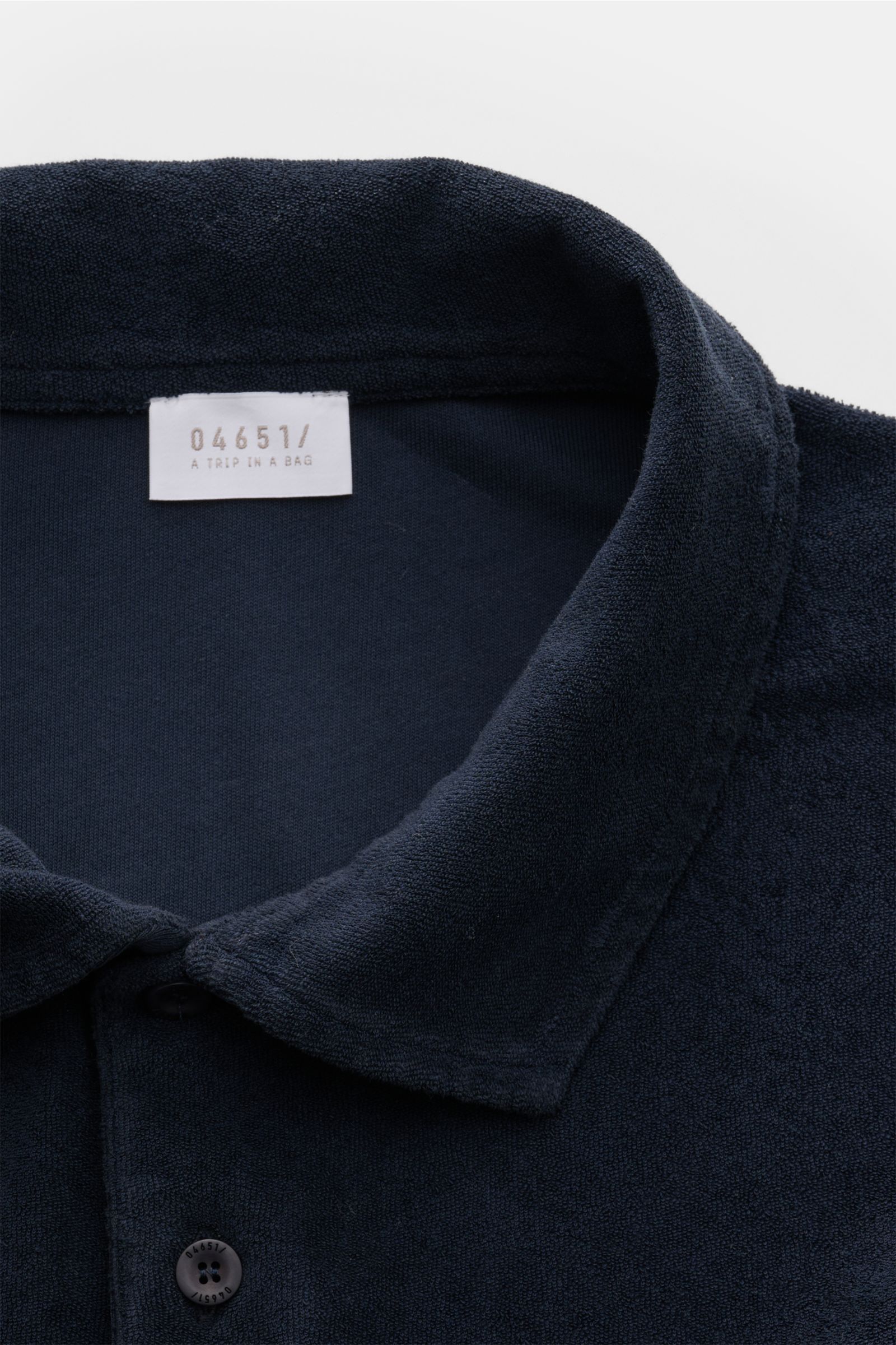 04651/ A trip in a bag Frottee-Poloshirt 'Terry Polo' navy aus reiner Baumwolle, weicher Griff, Regular Fit, Polokragen, Knopfleiste, Seitennahtlabel, kurze Saumschlitze, Nahaufnahme von oben.