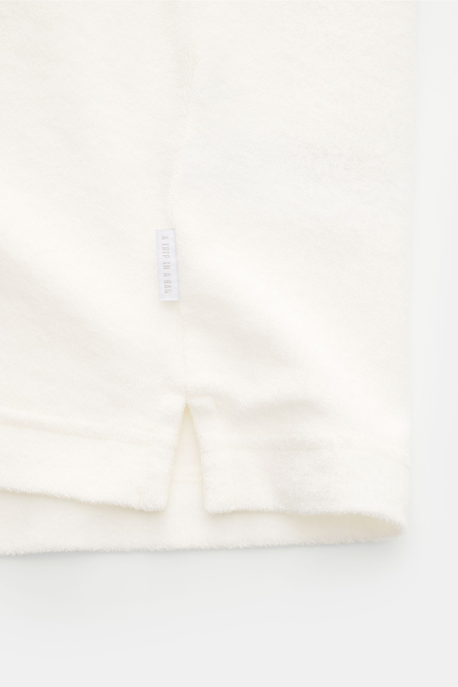 04651/ A trip in a bag Frottee-Poloshirt 'Terry Polo' offwhite, Detailfoto seitlich mit kurzem Saumschlitz, weicher Baumwollstoff, Weblabel.