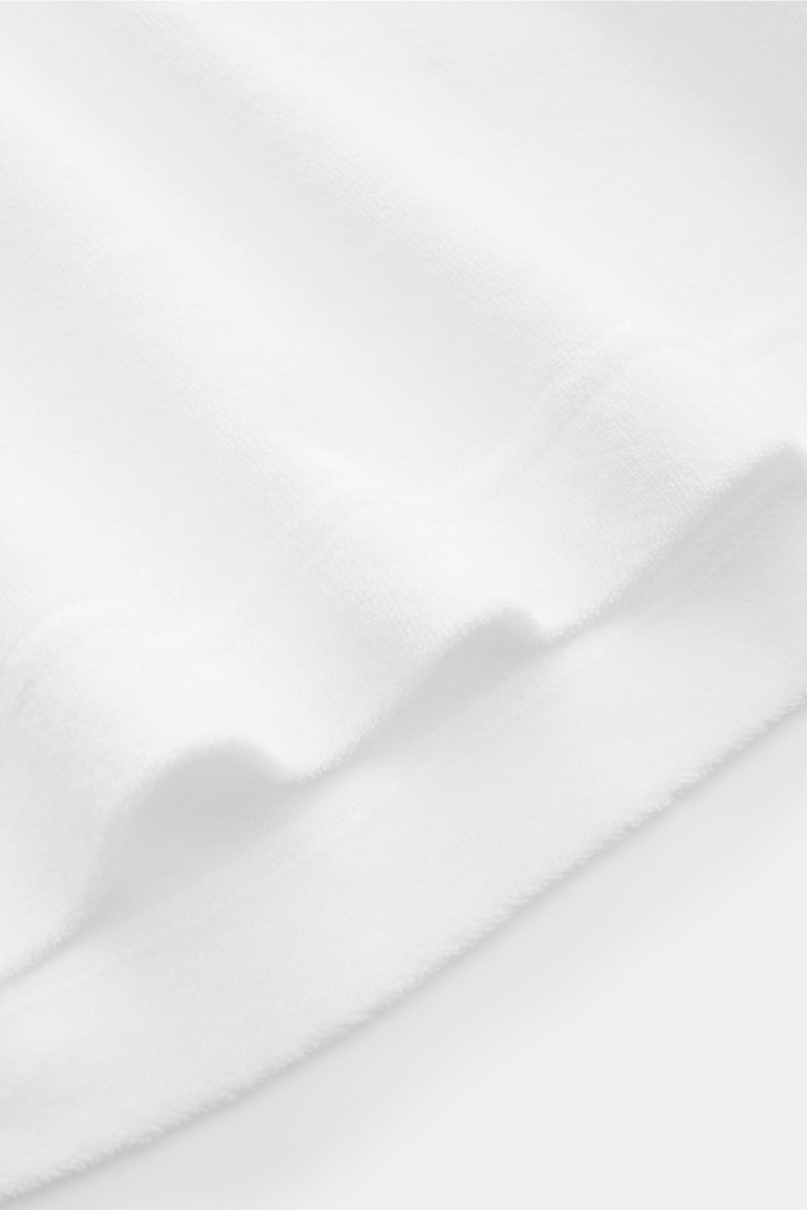 Weißes 04651/ A trip in a bag Frottee-Poloshirt 'Terry Polo' aus reiner Baumwolle, weich, Regular Fit, mit Polokragen, Knopfleiste, seitlichem Weblabel, kurze Saumschlitze, Detailaufnahme Stoffstruktur.