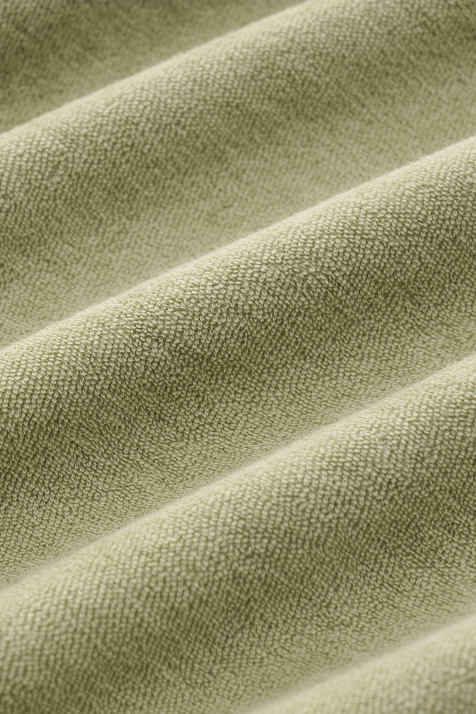 Nahaufnahme von salbeigrünem Frottee-Stoff des 04651/ A trip in a bag Frottee-Poloshirts 'Terry Polo' aus reiner Baumwolle mit weichem Griff.