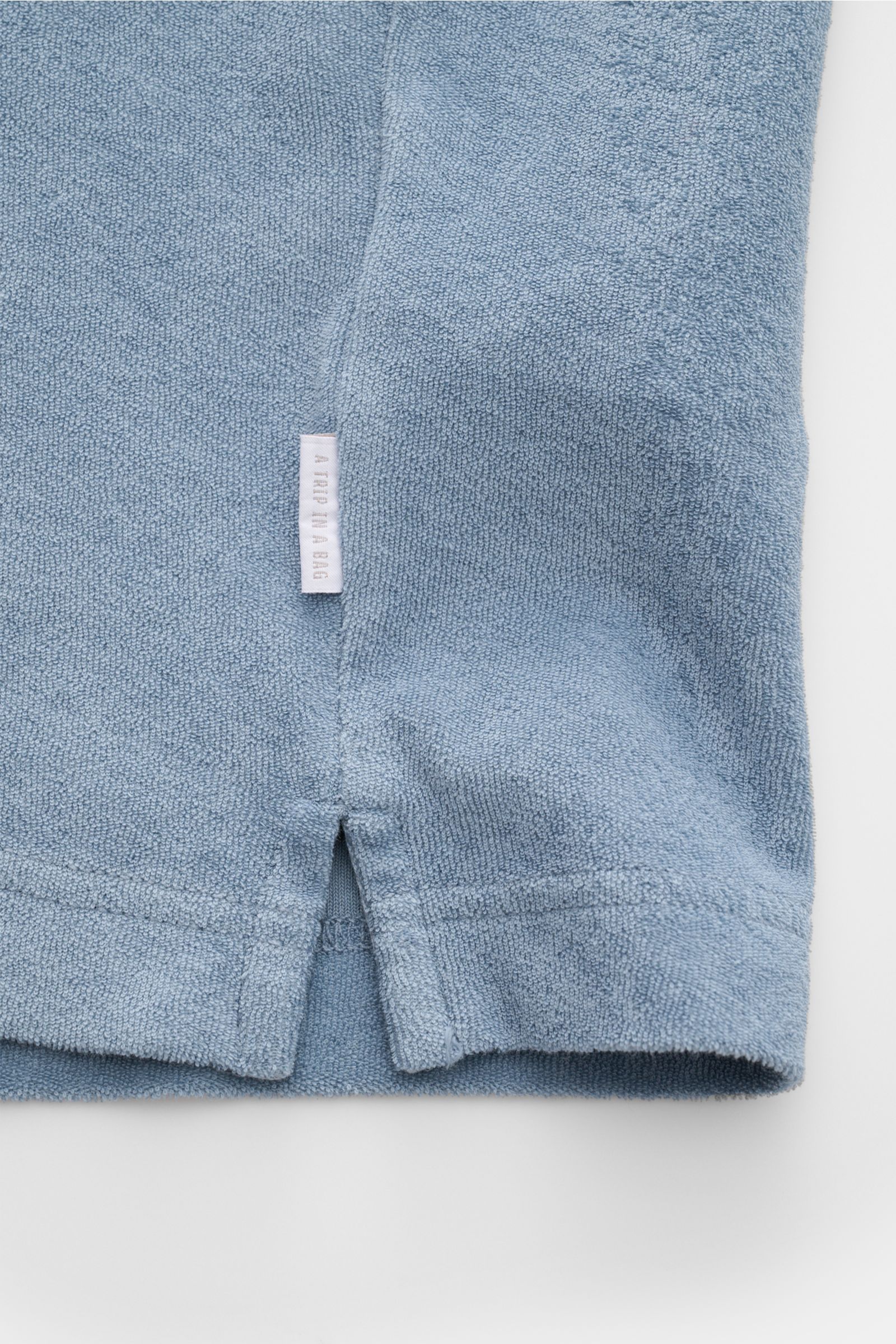 04651/ A trip in a bag Frottee-Poloshirt 'Terry Polo' rauchblau, Detailaufnahme unten mit kurzem Saumschlitz, weicher Baumwoll-Frottee, Weblabel.