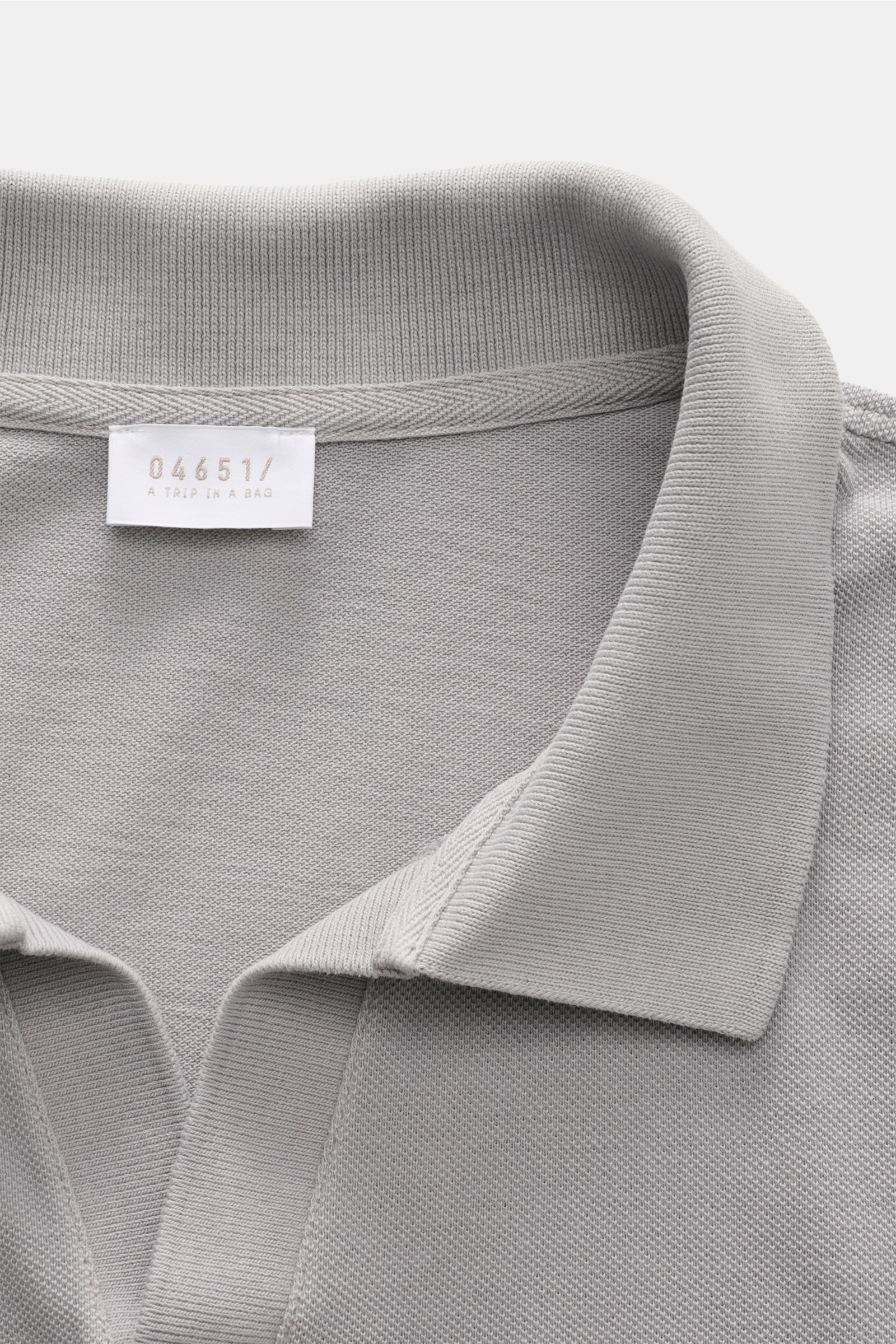 Close-up top-down view of the collar and label of the 04651/ A trip in a bag Polo shirt 'Johnny' grey in pure piqué cotton with open collar.

For relaxed casual looks: 04651/ A TRIP IN A BAG brings a relaxed summer vibe to your wardrobe with this pure 
