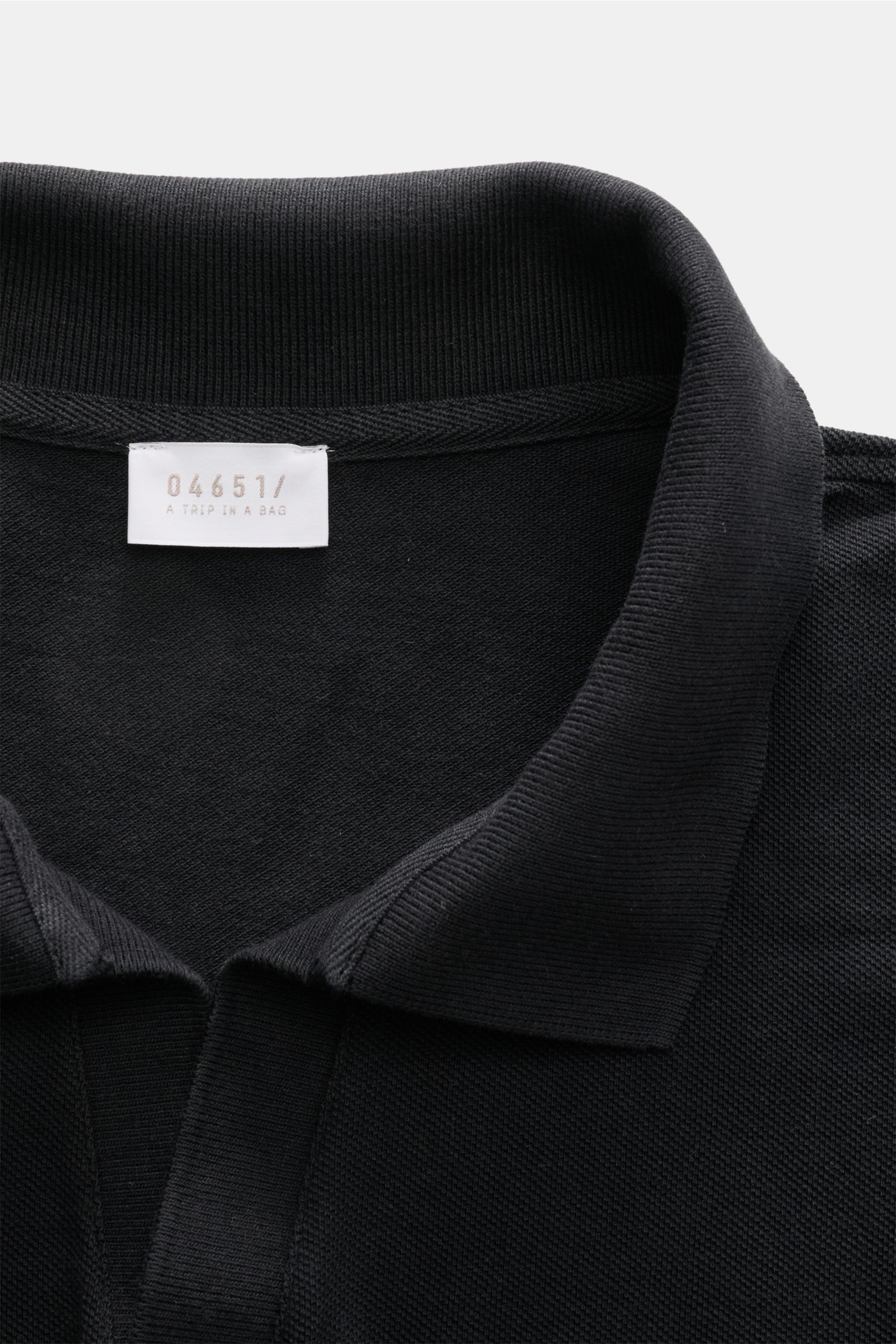 Close-up front view of the collar and label of the 04651/ A trip in a bag Polo shirt 'Johnny' anthracite, made of pure piqué cotton.

For relaxed casual looks: 04651/ A TRIP IN A BAG brings a relaxed summer vibe to your wardrobe with this pure cotton p