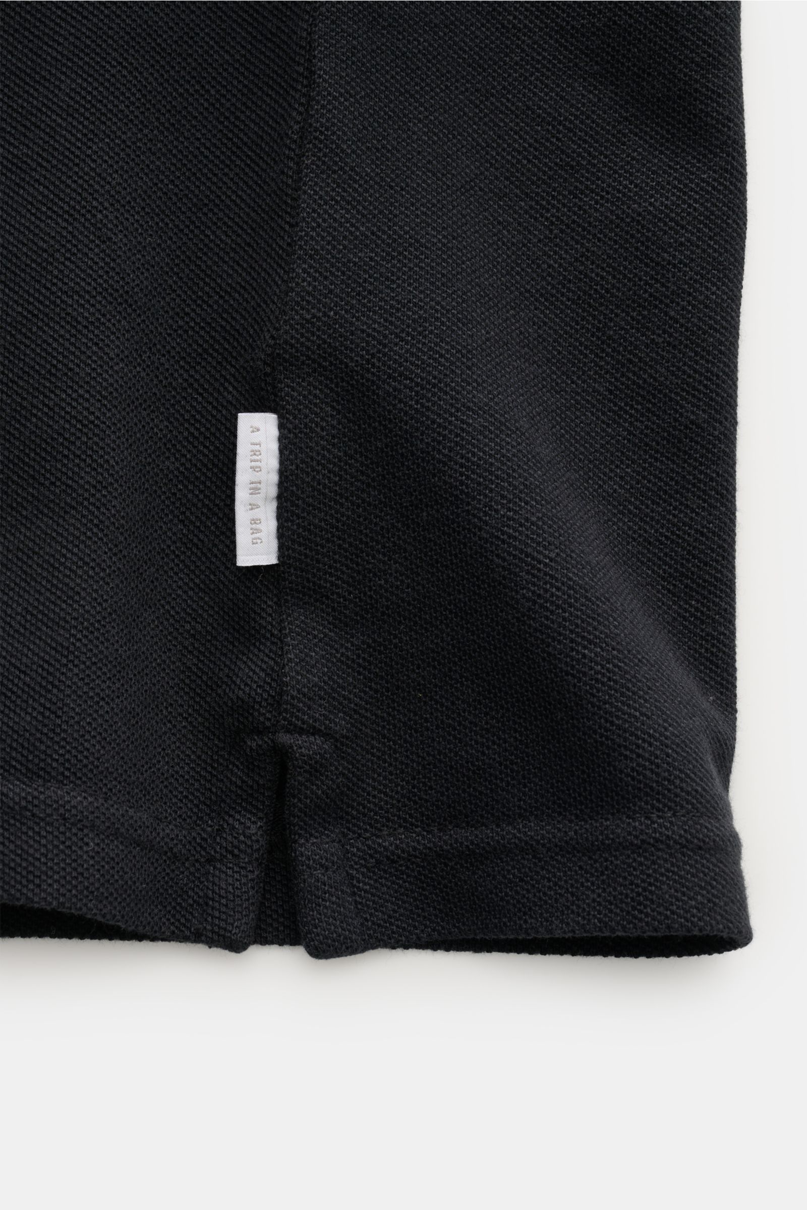 Close-up view of the lower side seam and hem of the 04651/ A trip in a bag Polo shirt 'Johnny' anthracite, showing pure piqué cotton fabric, small woven label, short hem vents, and slightly robust texture. 

For relaxed casual looks: 04651/ A TRIP IN A