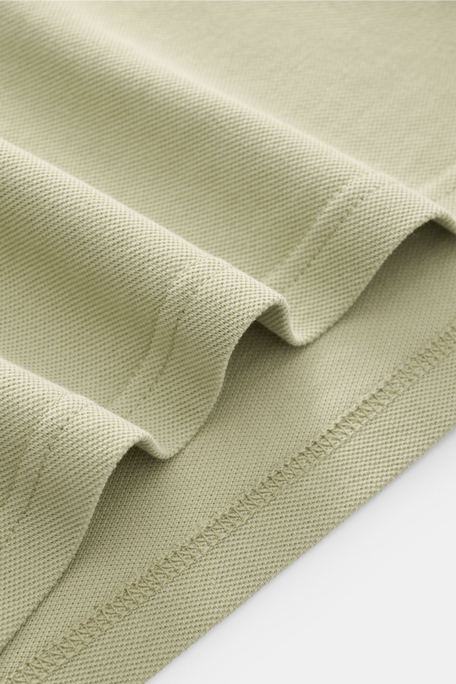 Nahaufnahme des saumigen Details vom 04651/ A trip in a bag Poloshirt 'Johnny' salbei aus Piqué-Baumwolle mit offener Kragenleiste.