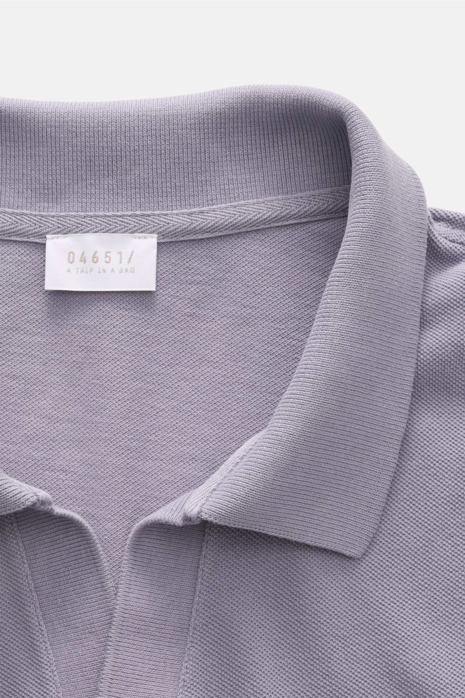 Nahaufnahme des violettfarbenen 04651/ A trip in a bag Poloshirt 'Johnny' lavender mit offenem Kragen aus reiner Baumwolle, Piqué-Struktur sichtbar.