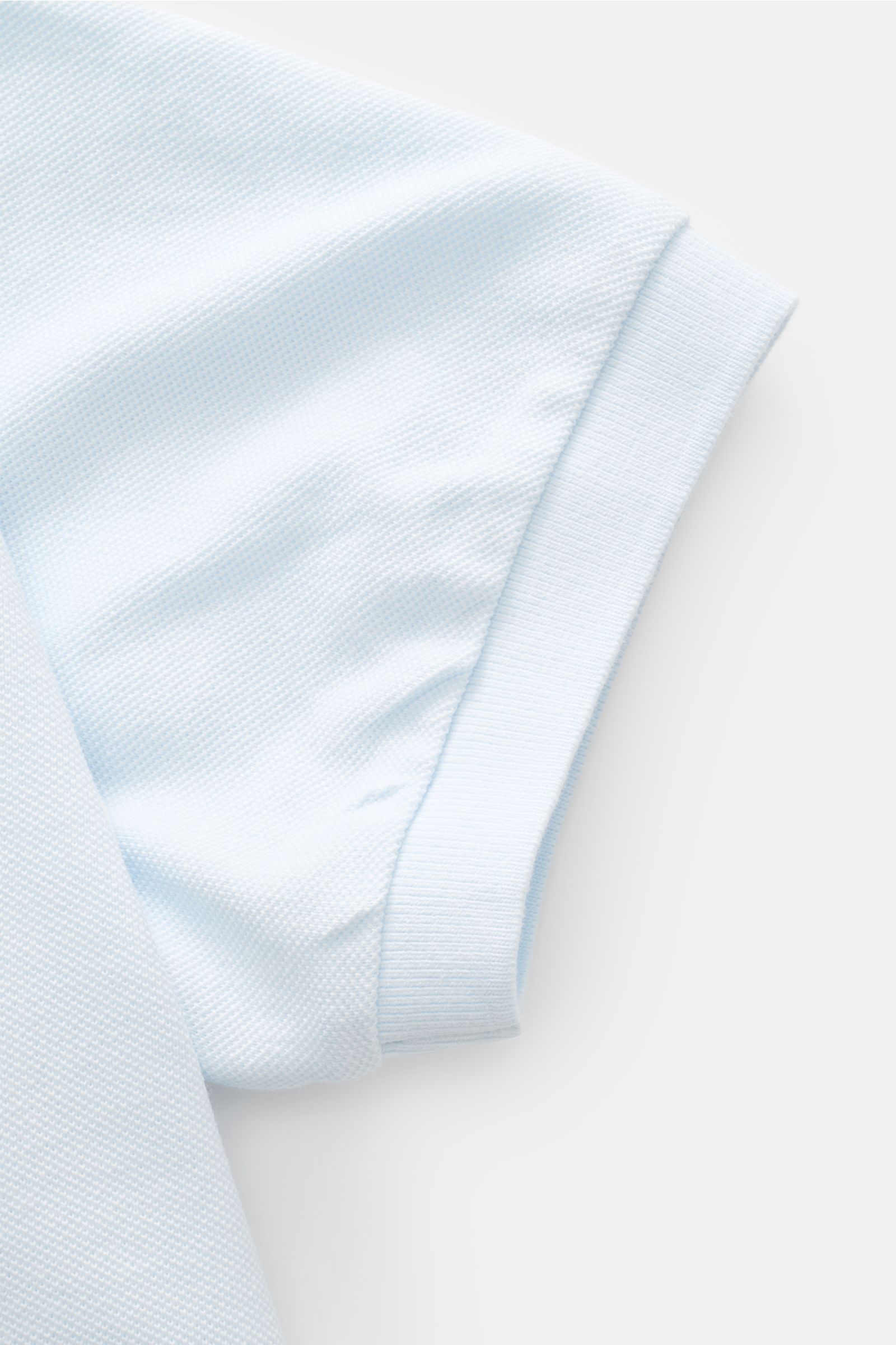 Nahaufnahme des Ärmels vom 04651/ A trip in a bag Poloshirt 'Johnny' pastellblau aus reiner Baumwolle mit Piqué-Struktur, offenem Kragen und Ärmelbündchen.