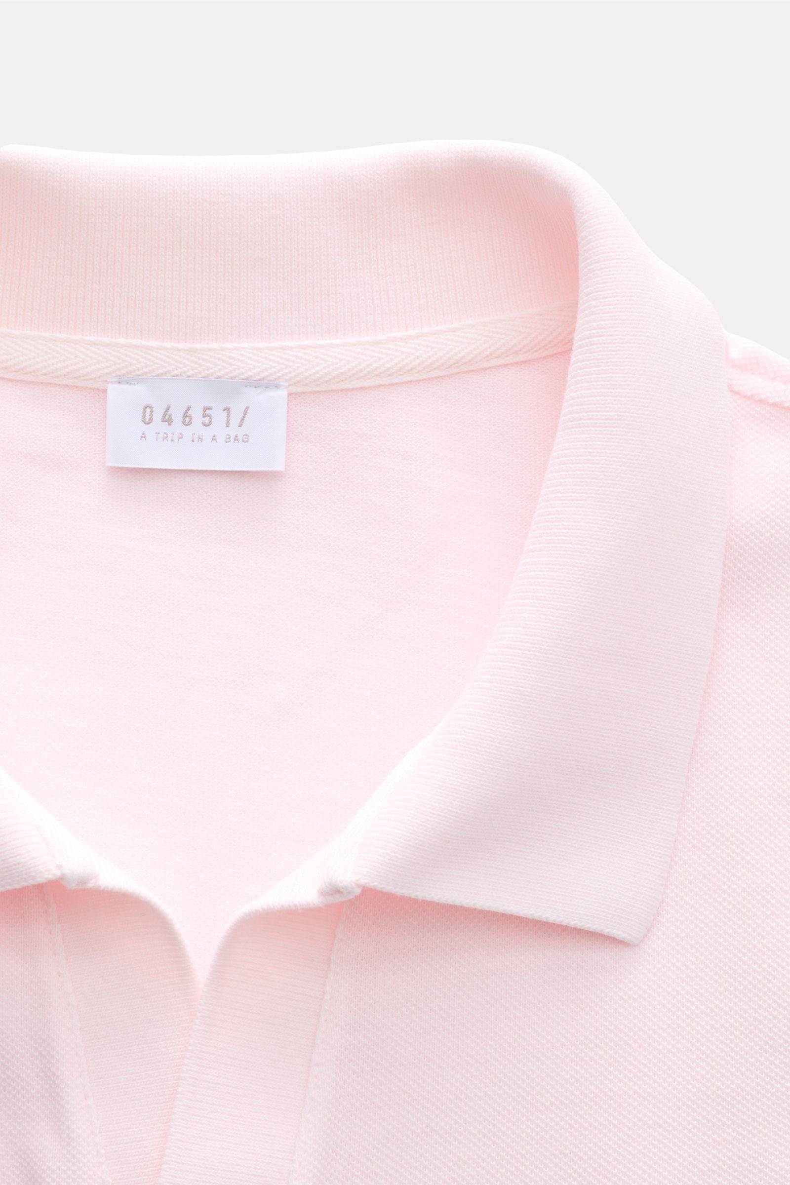 Nahaufnahme des Polokragens vom 04651/ A trip in a bag Poloshirt 'Johnny' rosé aus reiner Baumwolle mit offener Kragenleiste, fotografiert von oben.