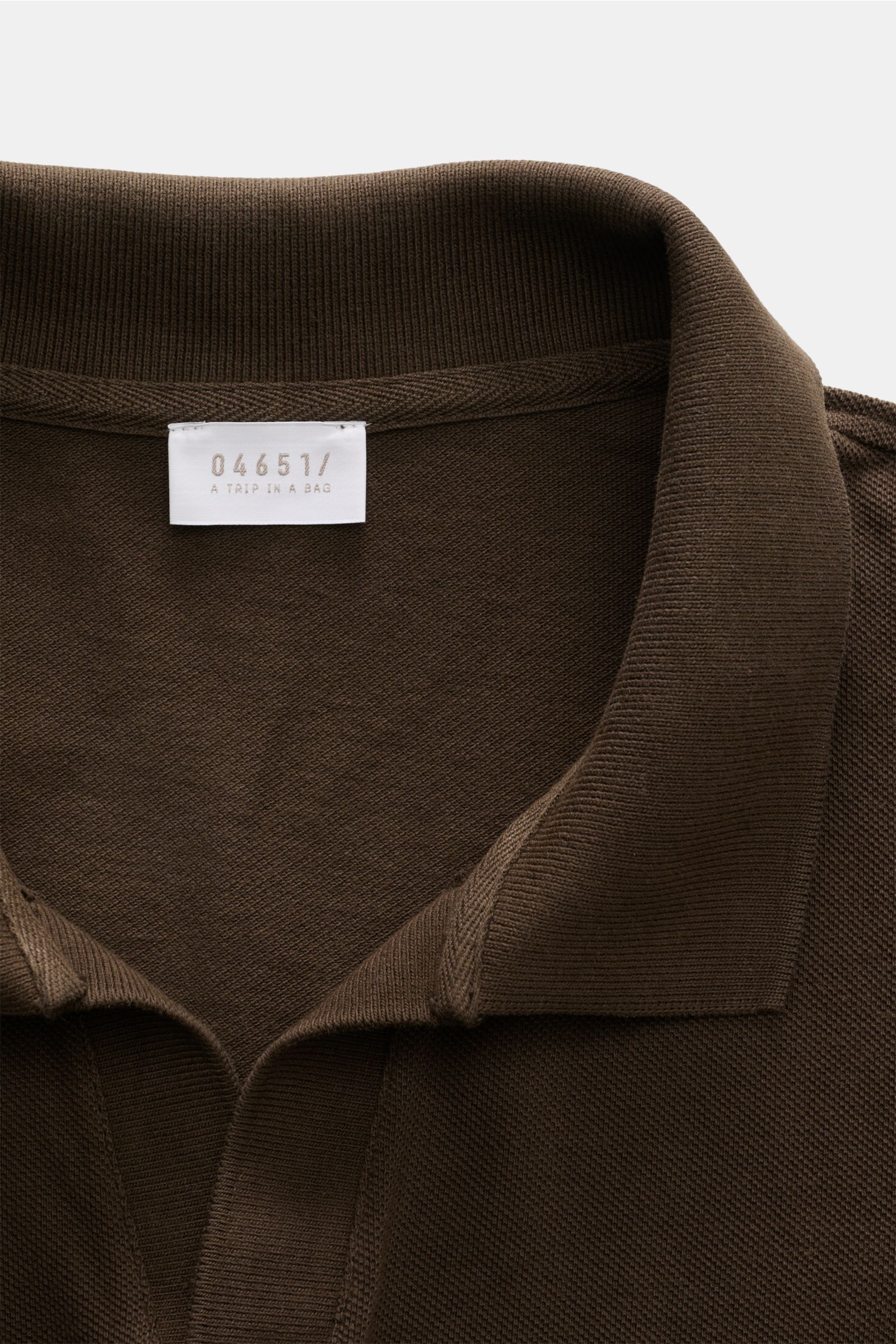 Close-up front view of the collar and label of the 04651/ A trip in a bag Polo shirt 'Johnny' dark brown in pure piqué cotton.

For relaxed casual looks: 04651/ A TRIP IN A BAG brings a relaxed summer vibe to your wardrobe with this pure cotton polo sh