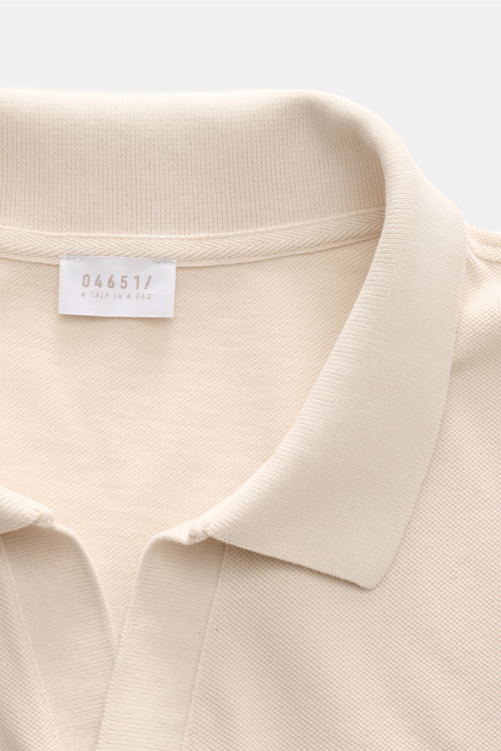 Close-up front view of the 04651/ A trip in a bag Poloshirt 'Johnny' sand showing collar and label, made of pure cotton piqué. 

Für lässige Freizeitlooks: 04651/ A TRIP IN A BAG bringt mit dem Poloshirt aus reiner Baumwolle und mit moderner, offener K