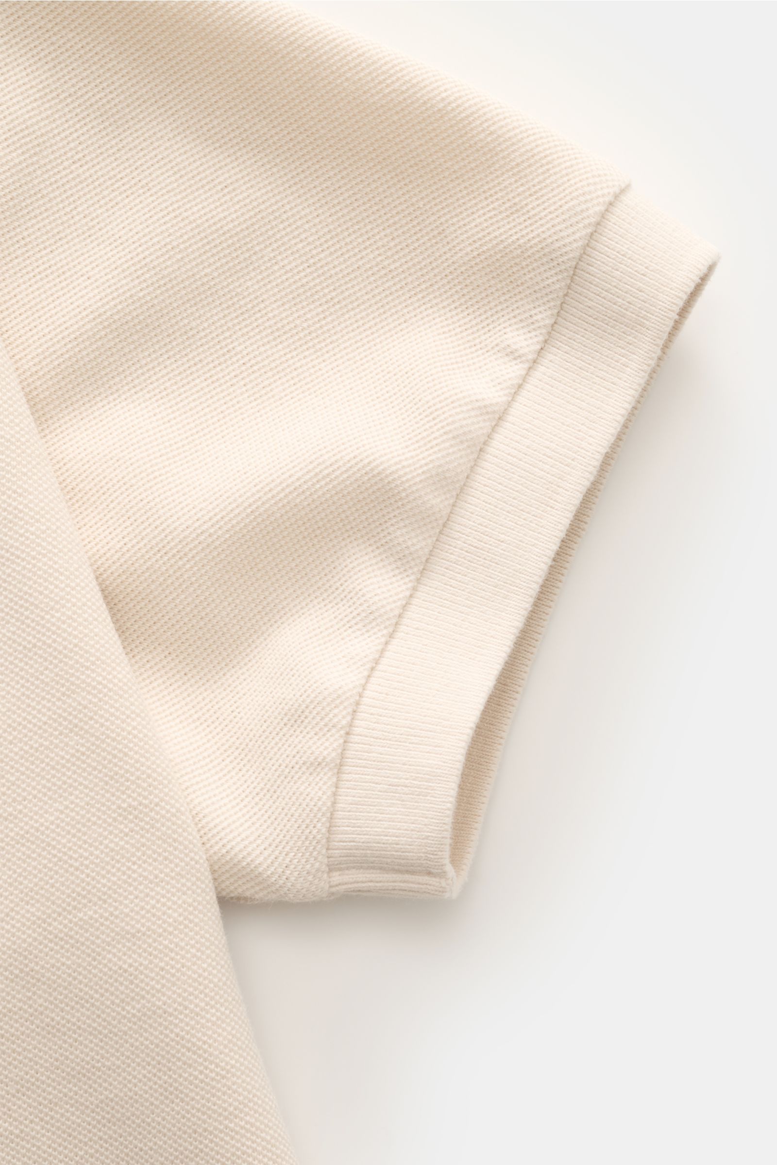 Close-up top view of the sleeve on the 04651/ A trip in a bag Poloshirt 'Johnny' sand, made of piqué cotton with ribbed cuff.

Für lässige Freizeitlooks: 04651/ A TRIP IN A BAG bringt mit dem Poloshirt aus reiner Baumwolle und mit moderner, offener Kra