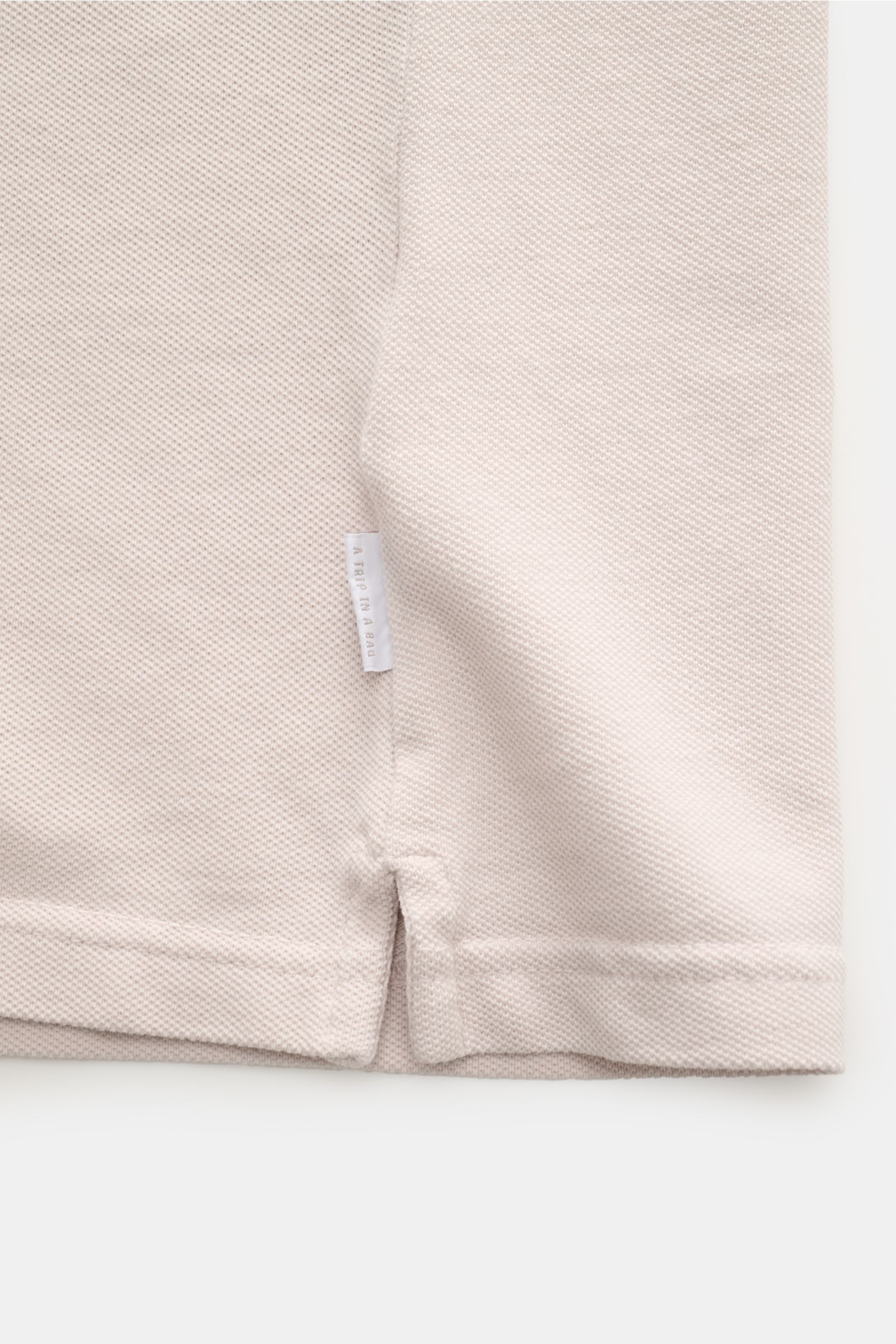 Close-up view of the hem and side seam of the 04651/ A trip in a bag Polo shirt 'Johnny' sand in pure piqué cotton fabric.

For relaxed casual looks: 04651/ A TRIP IN A BAG brings a relaxed summer vibe to your wardrobe with this pure cotton polo shirt 
