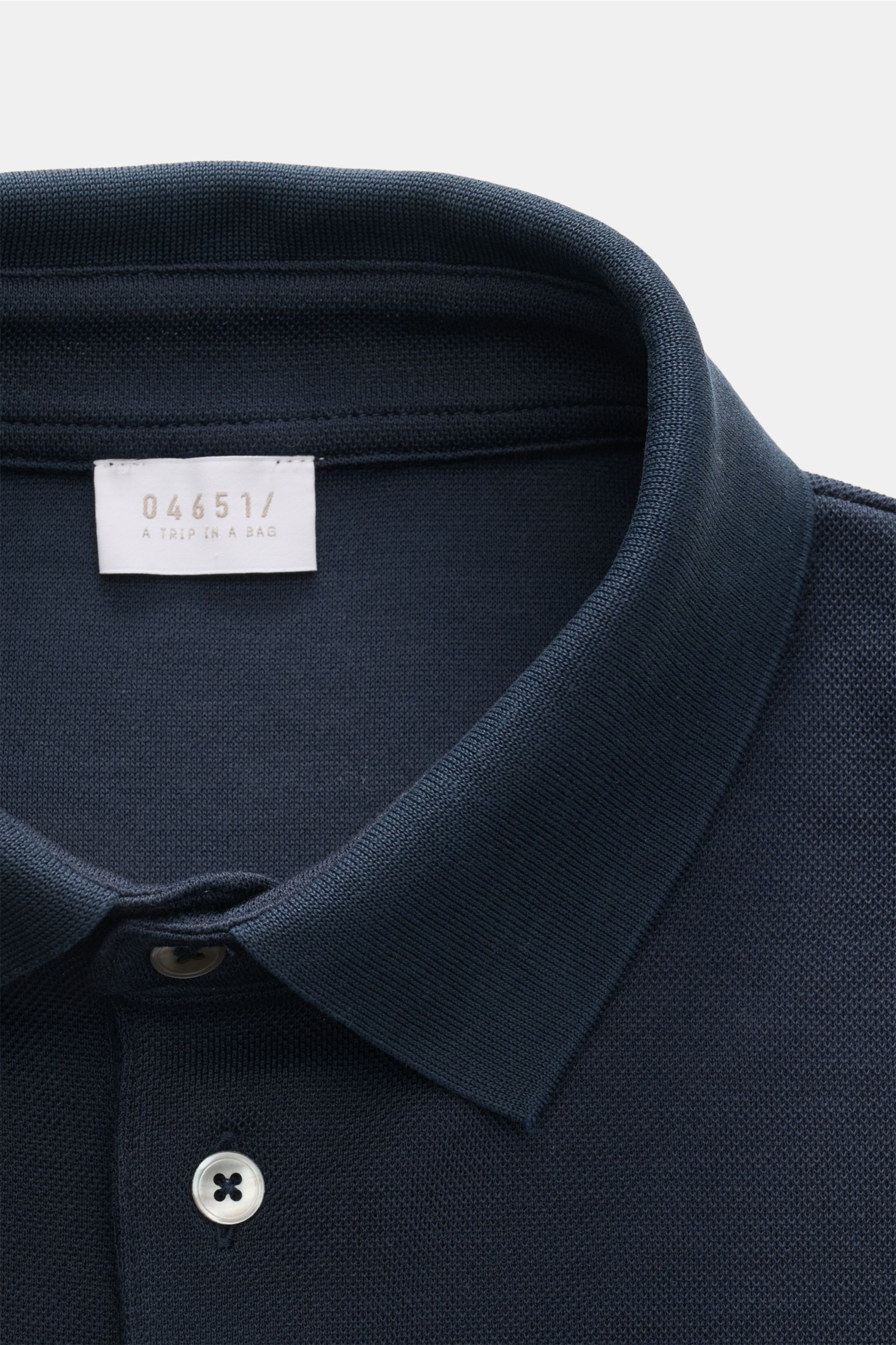 Nahaufnahme des Kragens und der Knopfleiste vom 04651/ A trip in a bag Poloshirt 'TP' navy aus reiner Baumwolle, Piqué, Regular Fit, mit weichem Griff, klassischem Polokragen, glatter Knopfleiste, kleinem Weblabel in der Seitennaht und komfortablen Rippbü