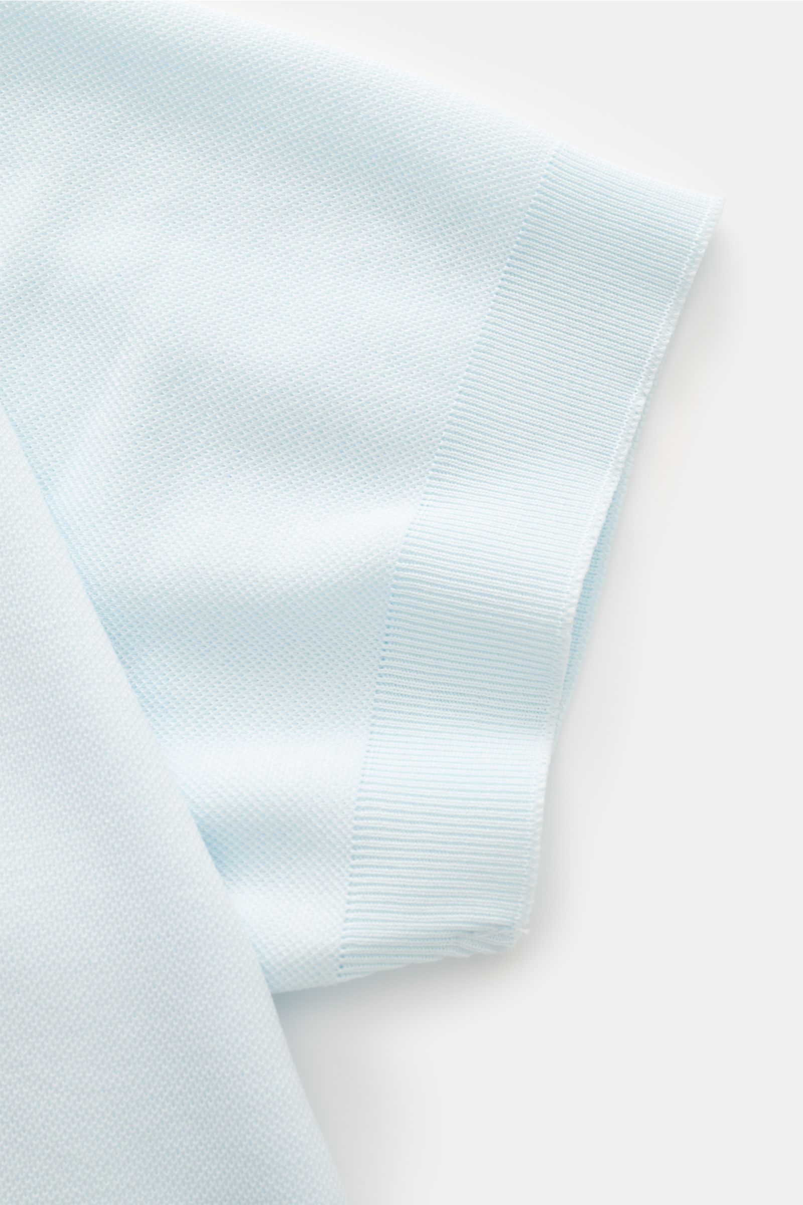 Close-up side view of the sleeve of the 04651/ A trip in a bag Poloshirt 'TP' pastellblau showing soft cotton piqué fabric, ribbed cuff, and smooth texture. Ob im Urlaub oder Office: 04651/ A TRIP IN A BAG bringt mit dem Poloshirt aus reiner Baumwolle 
