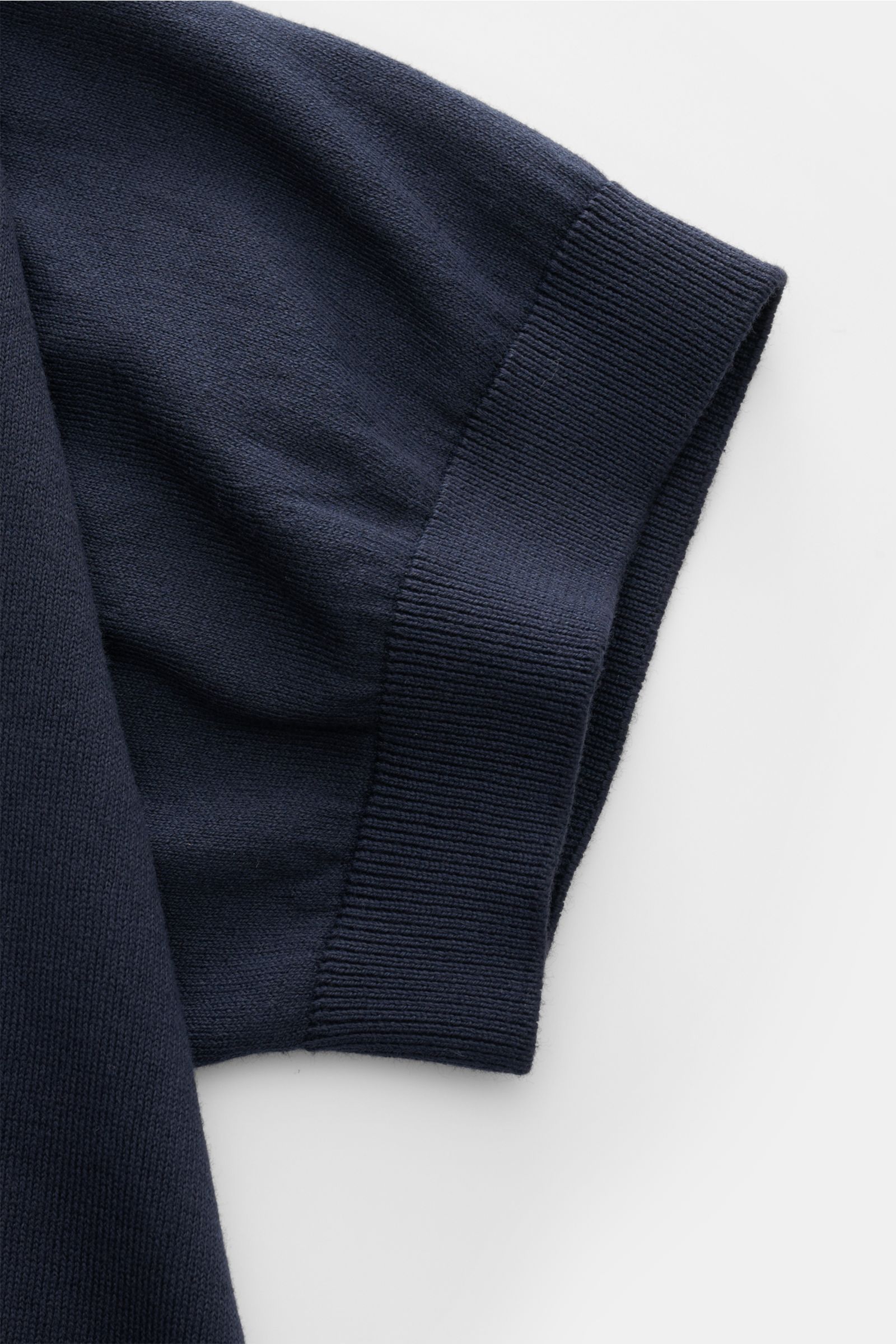 Nahaufnahme des Ärmels von dem 04651/ A trip in a bag Kurzarm-Strickpolo 'Pima Cotton' navy, gefertigt aus feiner Pima-Baumwolle, Feinstrick mit weichem Griff, sehr feinem Strickbild, Slim Fit, gestricktem Polokragen, Drei-Knopf-Leiste und flexiblen Rippb
