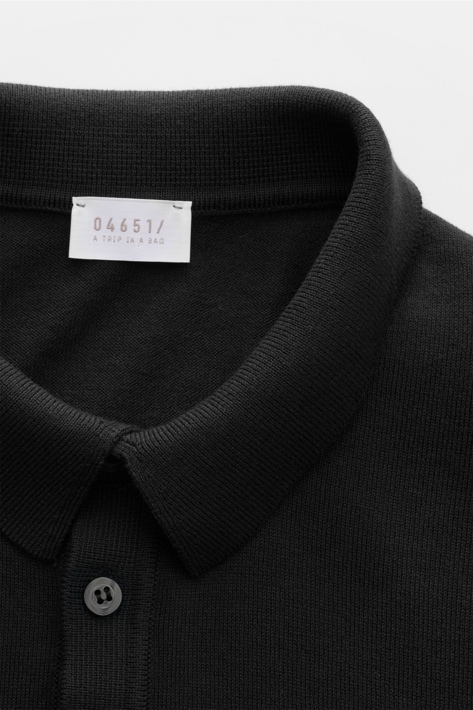 Nahaufnahme von 04651/ A trip in a bag Kurzarm-Strickpolo 'Pima Cotton' schwarz, feines Strickpolo aus reiner Pima-Baumwolle, Slim Fit, Polokragen, Drei-Knopf-Leiste, flexible Rippbündchen, weicher Griff, feines Strickbild, gesehen von oben auf Kragen und
