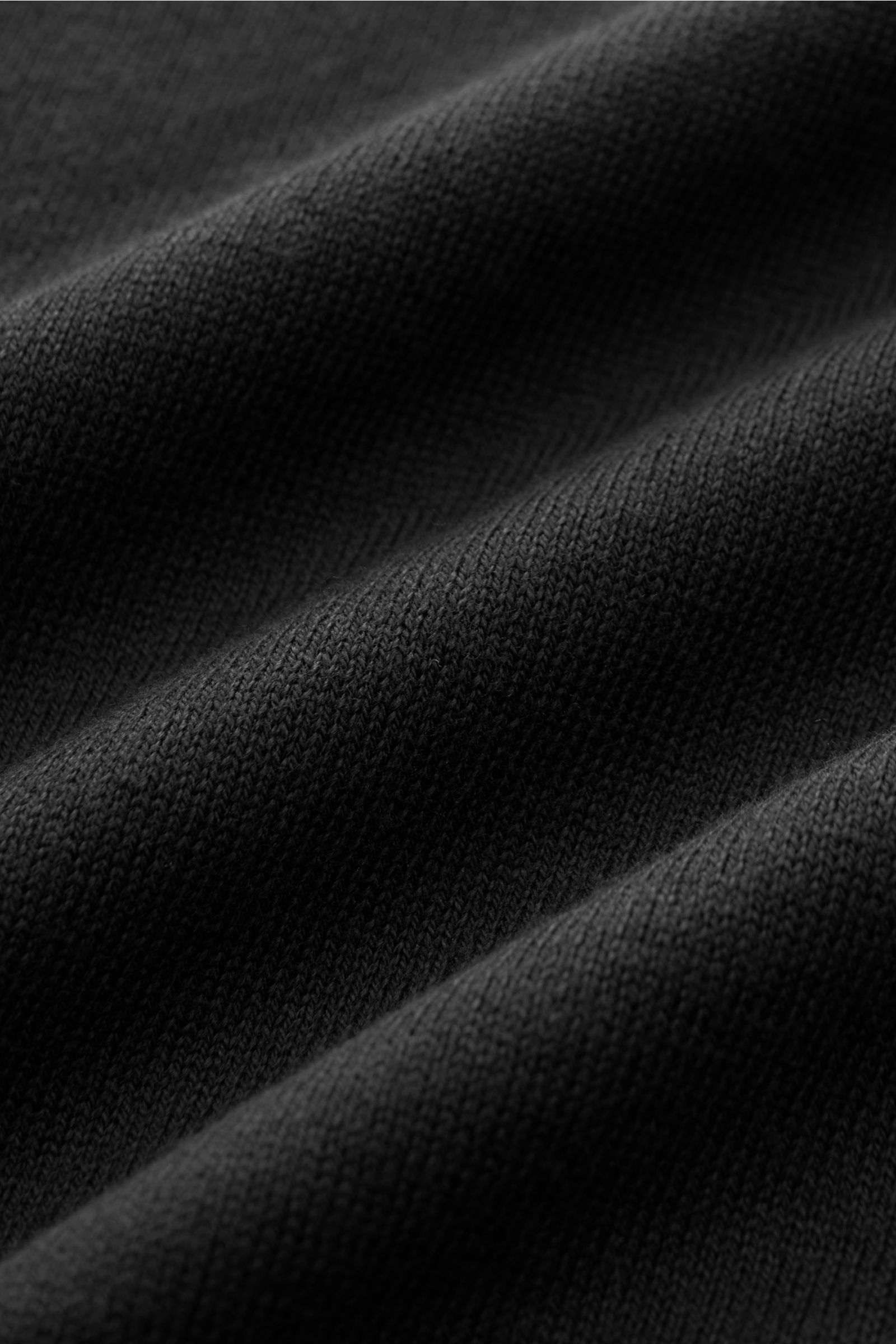 Schwarzer Feinstrick in Nahaufnahme, zeigt das sehr feine Strickbild des 04651/ A trip in a bag Kurzarm-Strickpolo 'Pima Cotton' schwarz aus Pima-Baumwolle.