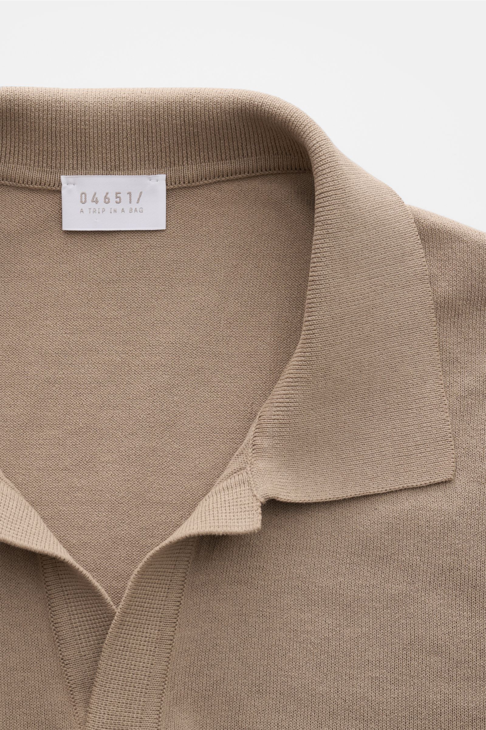 Nahaufnahme des taupefarbenen 04651/ A trip in a bag Kurzarm-Strickpolo 'Johnny' mit klassischem Polokragen, weichem Griff und feinem Strickbild, fotografiert von oben für legere Frühlingslooks aus reiner Baumwolle im Regular Fit mit komfortablen Rippbünd