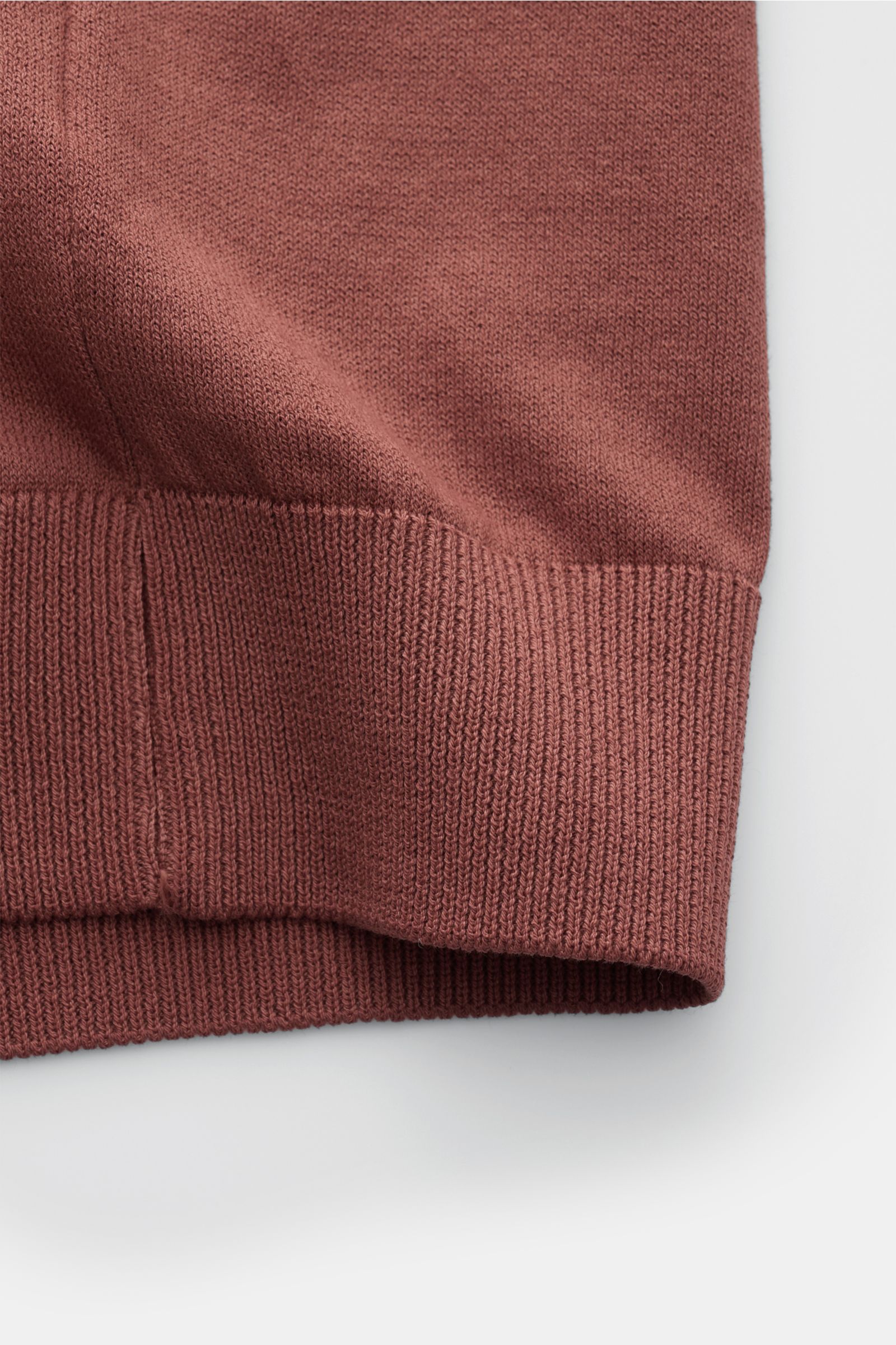 Nahaufnahme des Saums vom 04651/ A trip in a bag Kurzarm-Strickpolo 'Johnny' rostbraun, aus reiner Baumwolle mit weichem Griff und feinem Strickbild, Regular Fit, klassischer Polokragen und komfortablen Rippbündchen, fotografiert von unten.