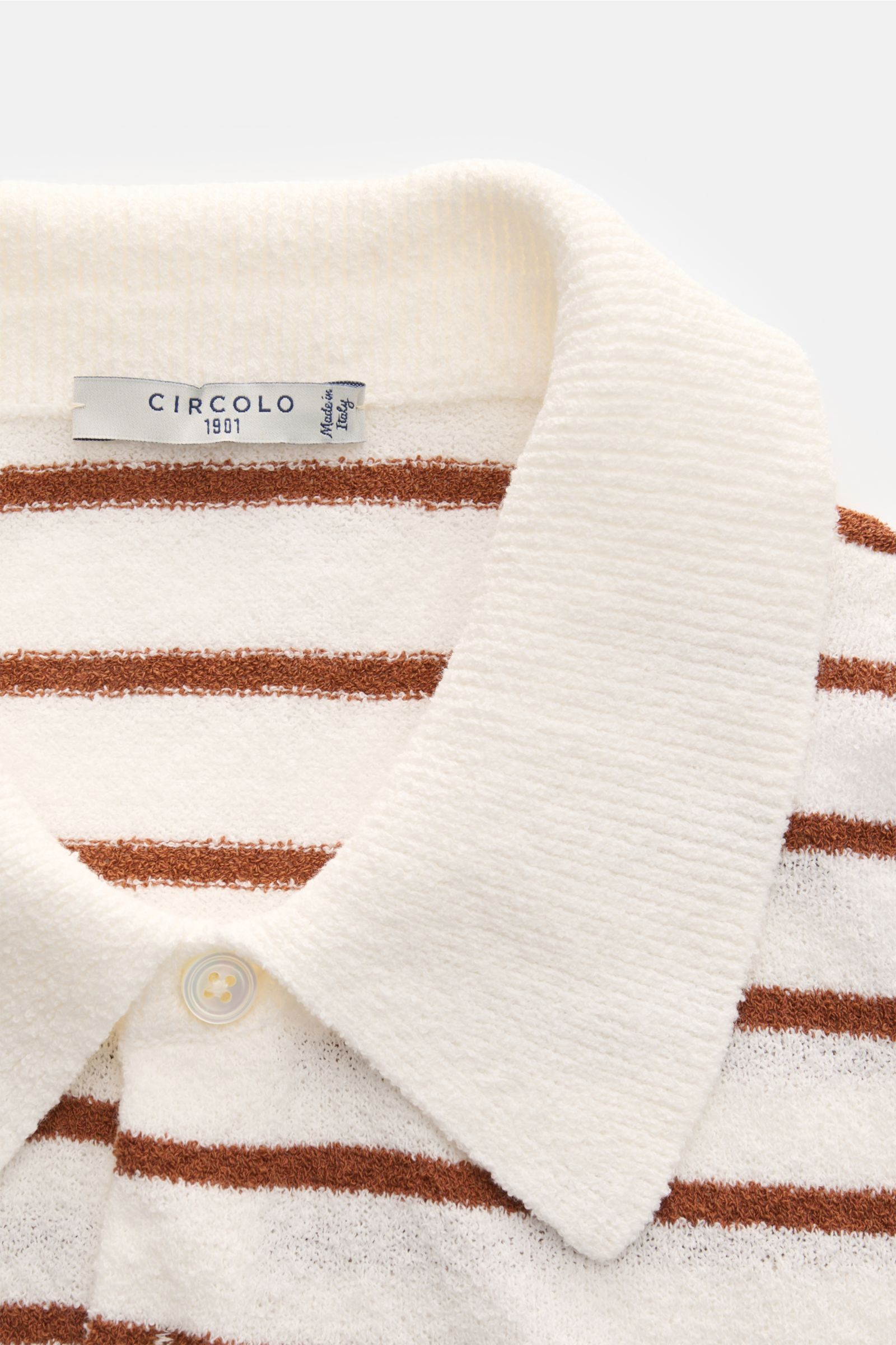 Close-up front view of the Circolo 1901 Frottee-Kurzarm-Strickpolo weiß/braun gestreift showing its soft, textured white terry knit fabric with slim brown stripes, classic polo collar, and a three-button placket. Sommer-Essential mit Charakter: Das Pol