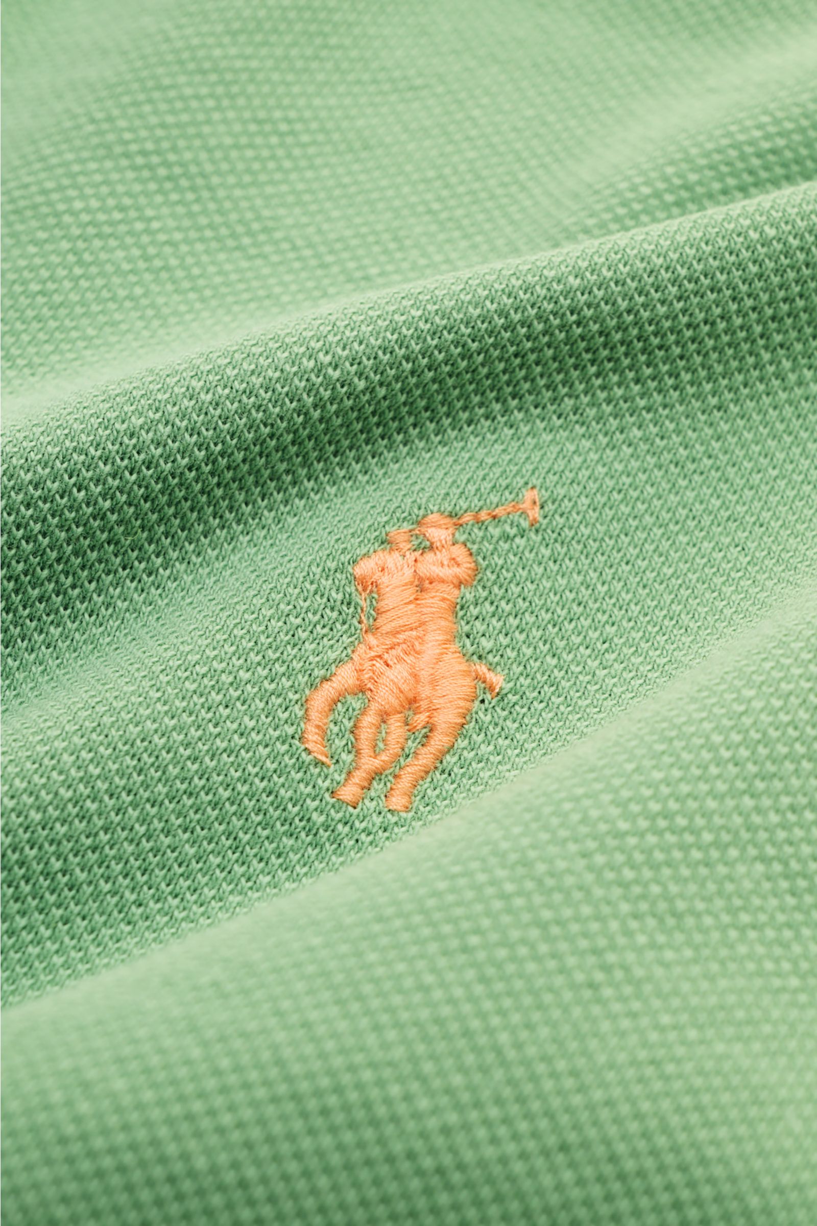 Nahaufnahme des mintgrünen Polo Ralph Lauren Poloshirts aus Baumwoll-Piqué mit kontrastierendem orangefarbenem Logo-Stitching.