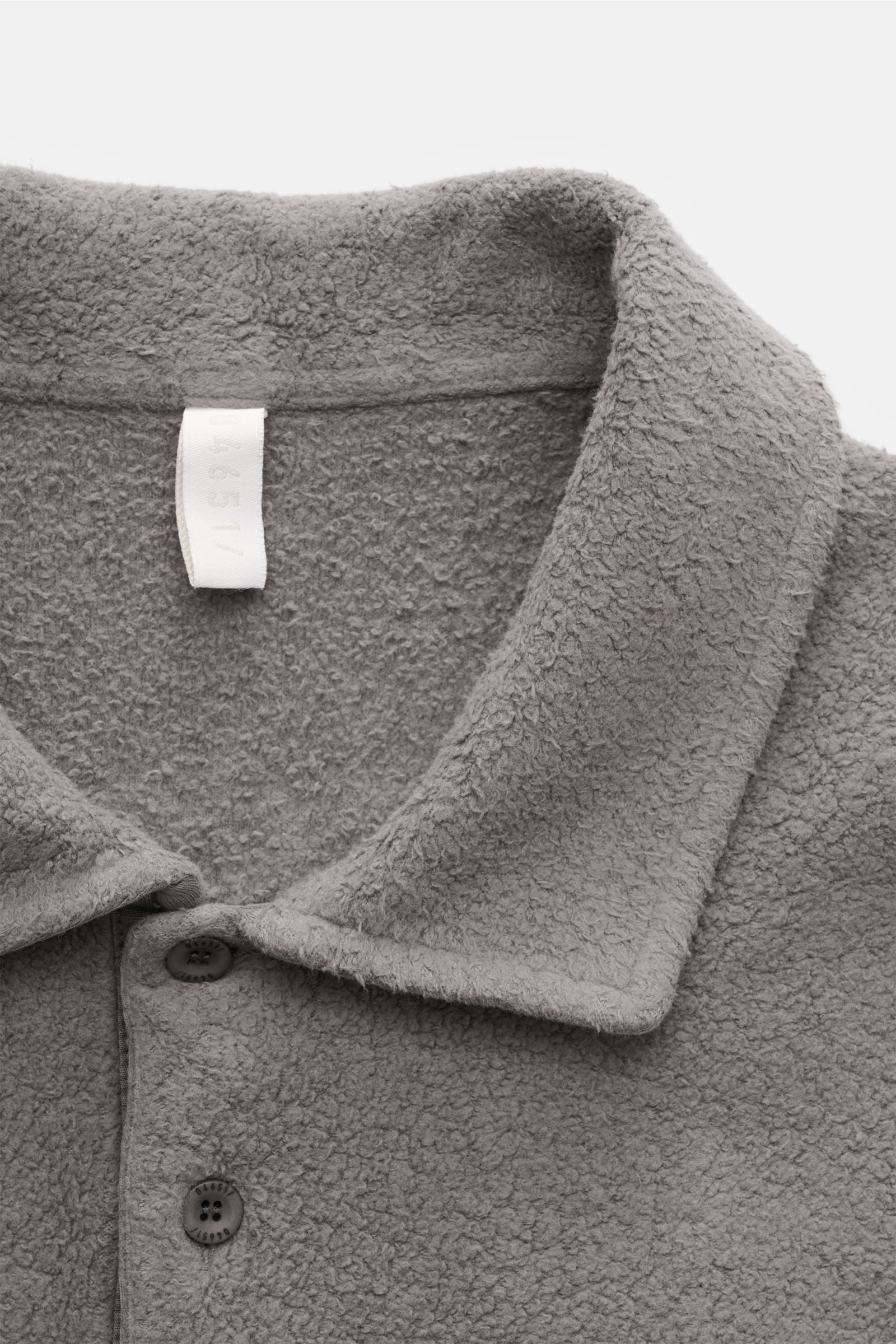 Nahaufnahme des dunkelgrauen 04651/ A trip in a bag Fleece Langarm-Poloshirt von schräg oben, Fleece aus reiner Baumwolle, softer Griff, garment dyed, Regular Fit, typischer Polokragen, Drei-Knopf-Leiste, kleines Weblabel in der Seitennaht, kurze Saumschl