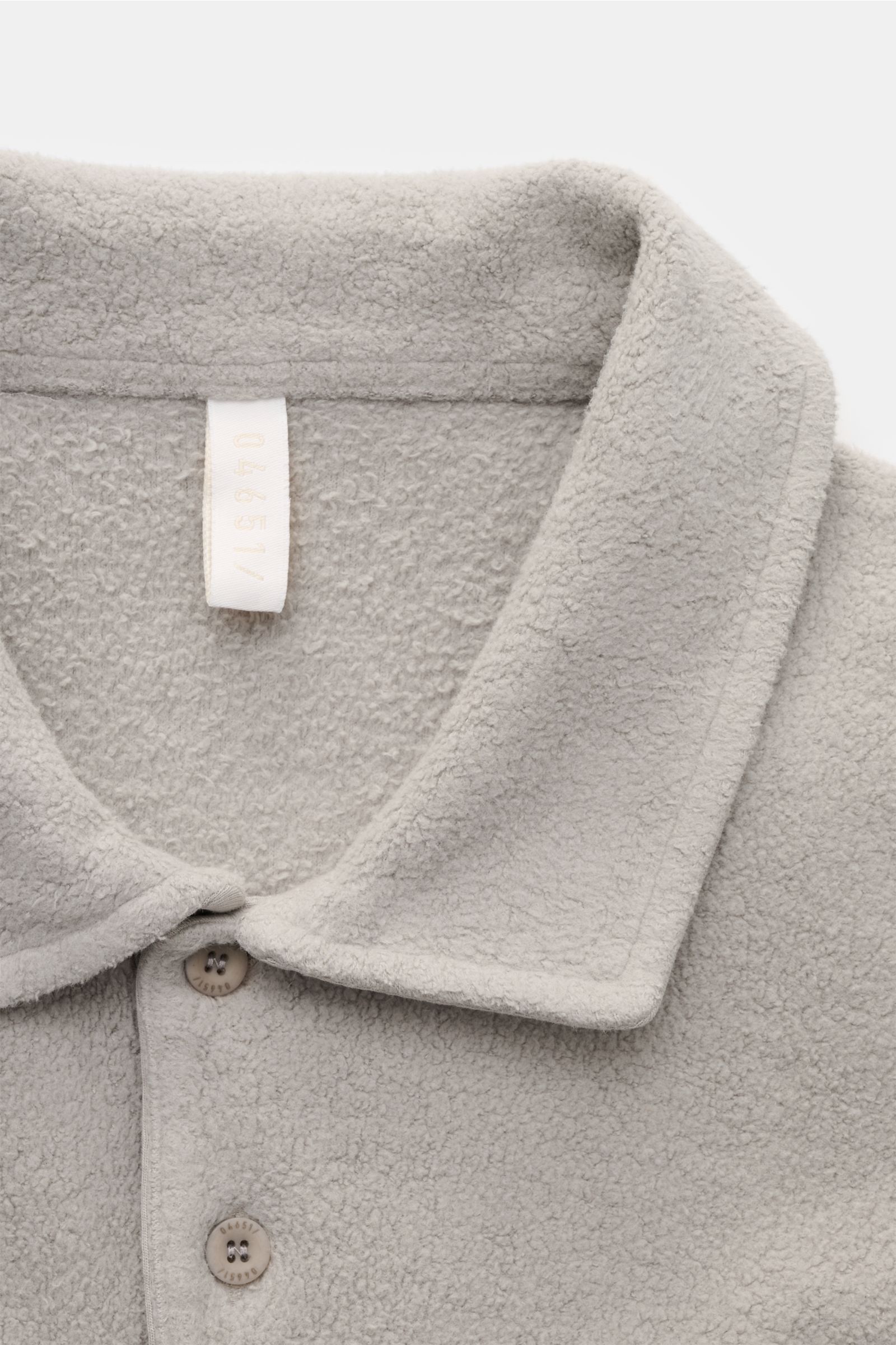 Nahaufnahme des grauen 04651/ A trip in a bag Fleece Langarm-Poloshirts aus reiner Baumwolle, softem Griff, garment dyed, Regular Fit, mit typischem Polokragen, Drei-Knopf-Leiste, kleinem Weblabel in der Seitennaht und kurzen Saumschlitzen, aus schräger P