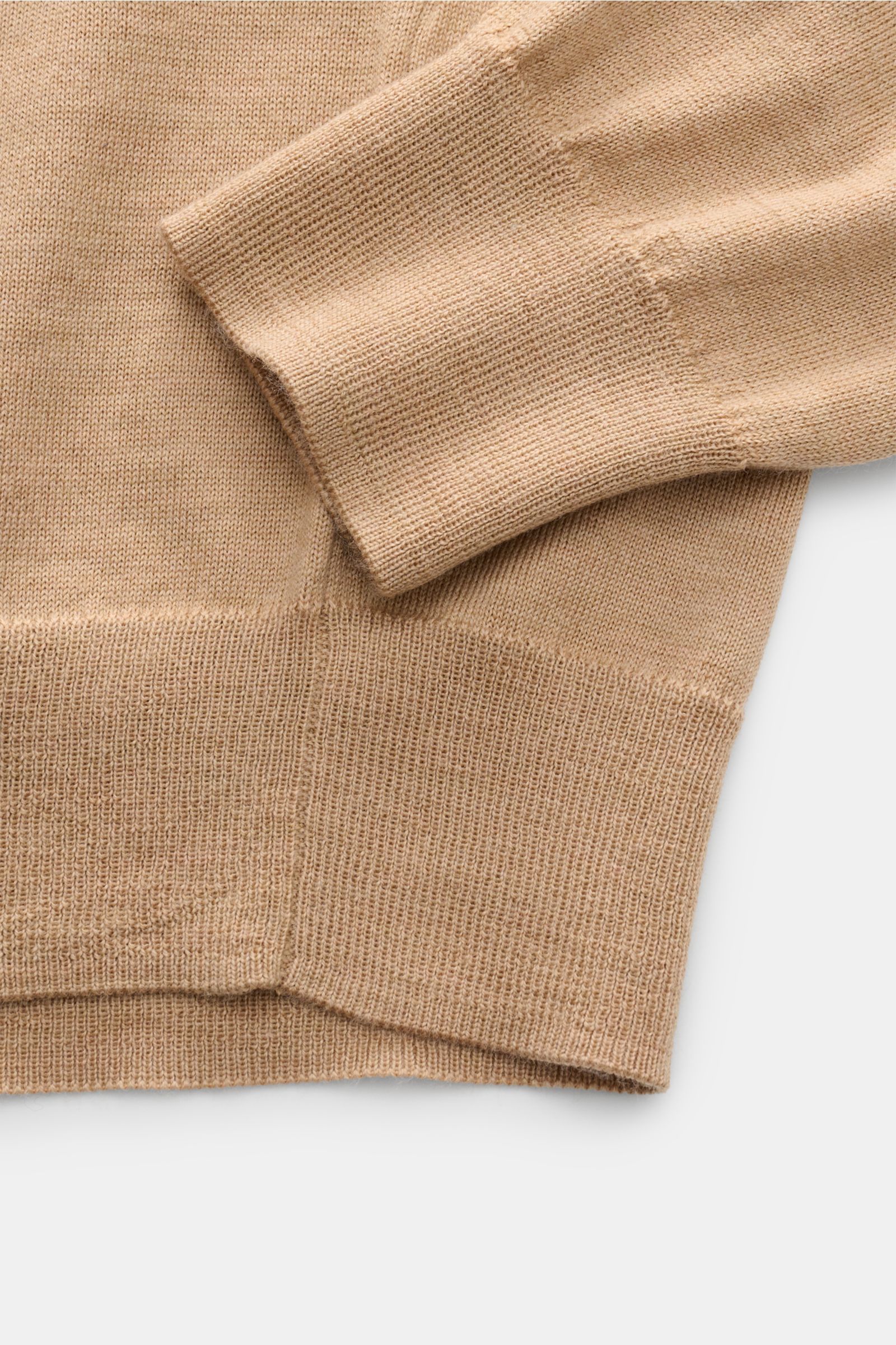 Beige Polo Ralph Lauren Strickpolo aus reiner, weicher Wolle mit feinem Strickbild, elastischem Rippbündchen, Nahaufnahme von Ärmel und Saum.