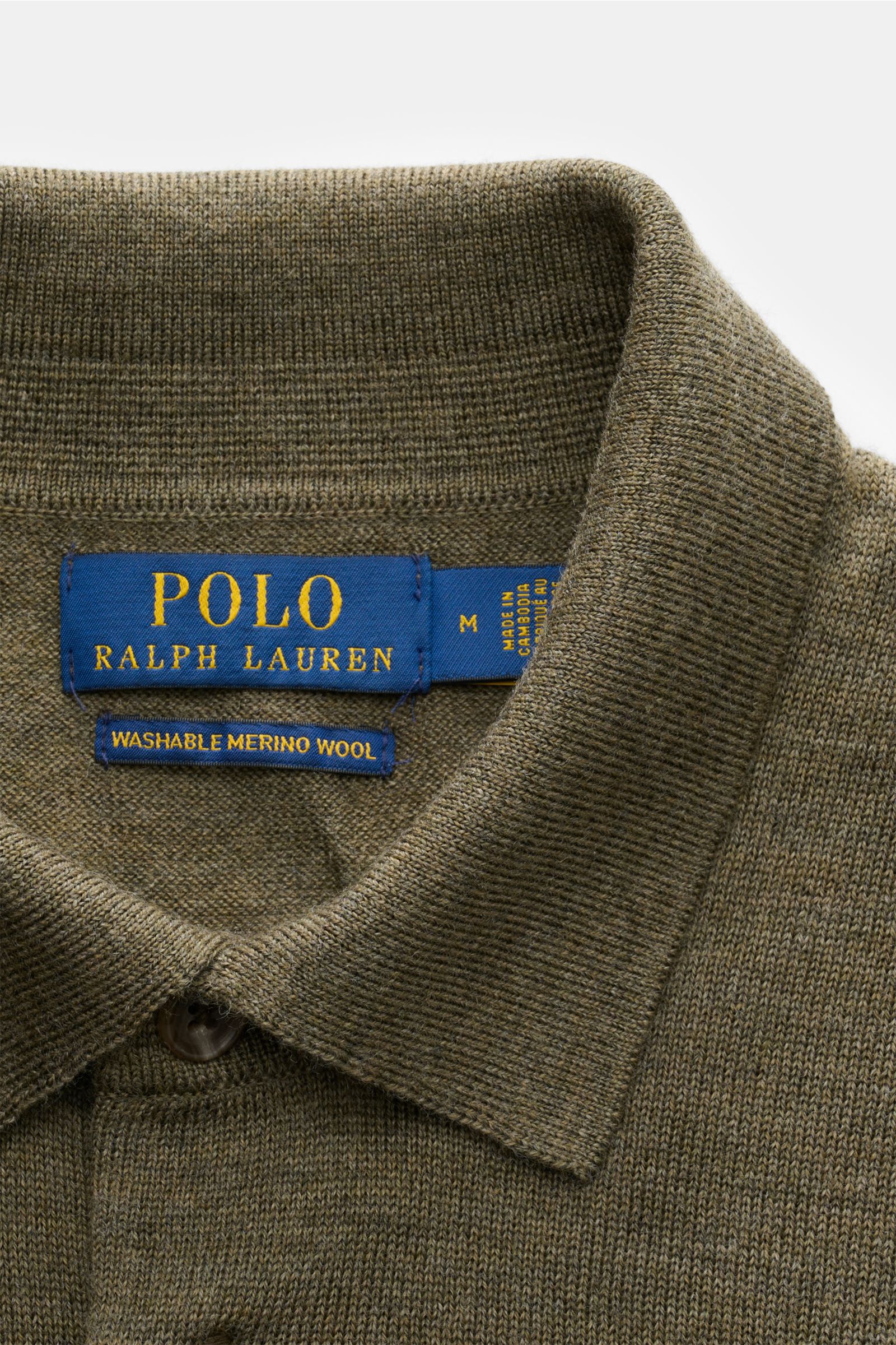 Close-up front view of Polo Ralph Lauren Strickpolo oliv meliert showing knitted collar and button placket with label.

Mit diesem Strickpolo aus reiner, softer Wolle mit feinem Strickbild bietet POLO RALPH LAUREN ein wärmendes Basic für die neue Saiso